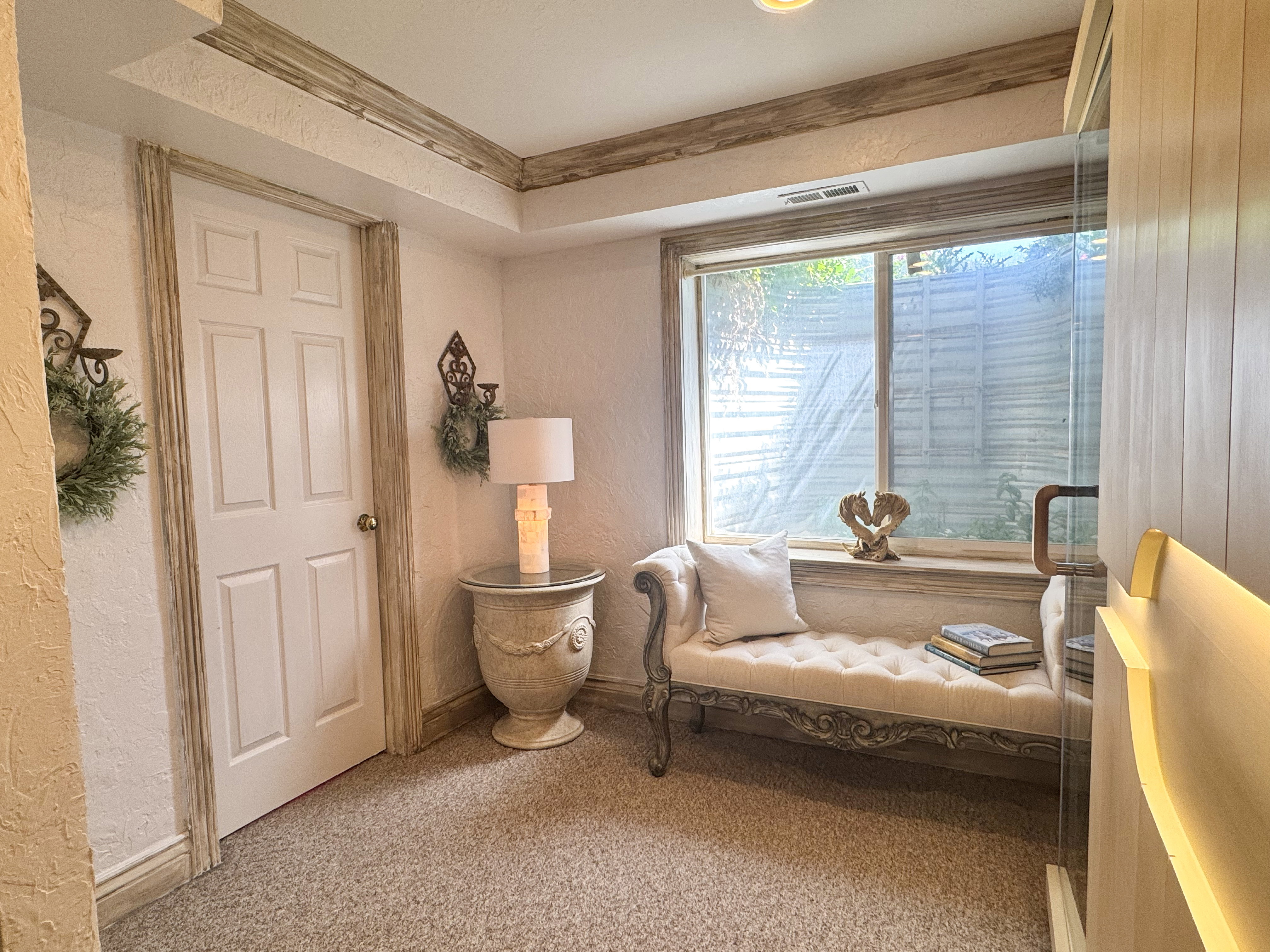 Carpeted floor with a window, white panel door, and decorative trim details