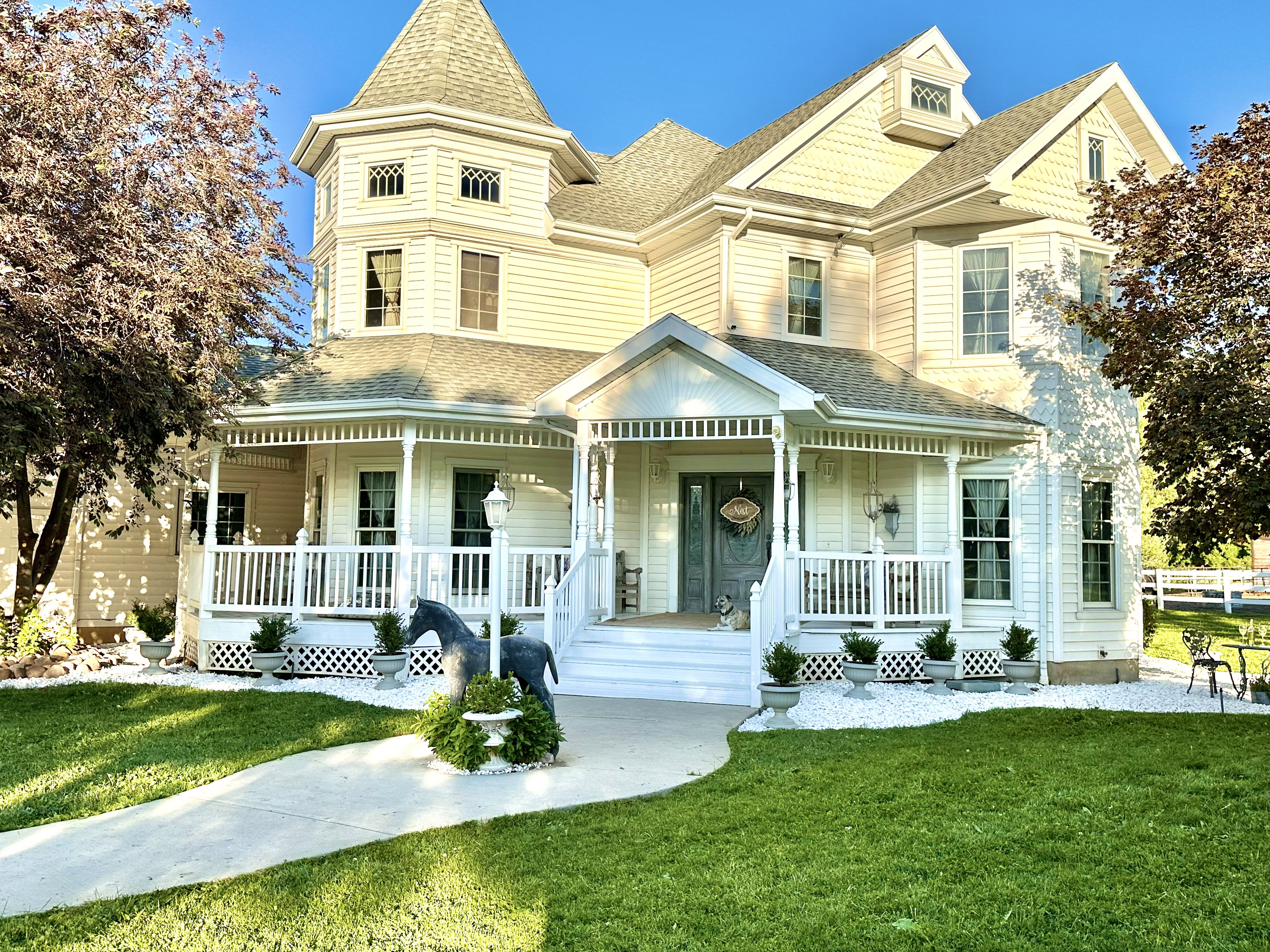 Victorian-style exterior featuring a prominent turret, wraparound porch with white balusters, and gabled rooflines