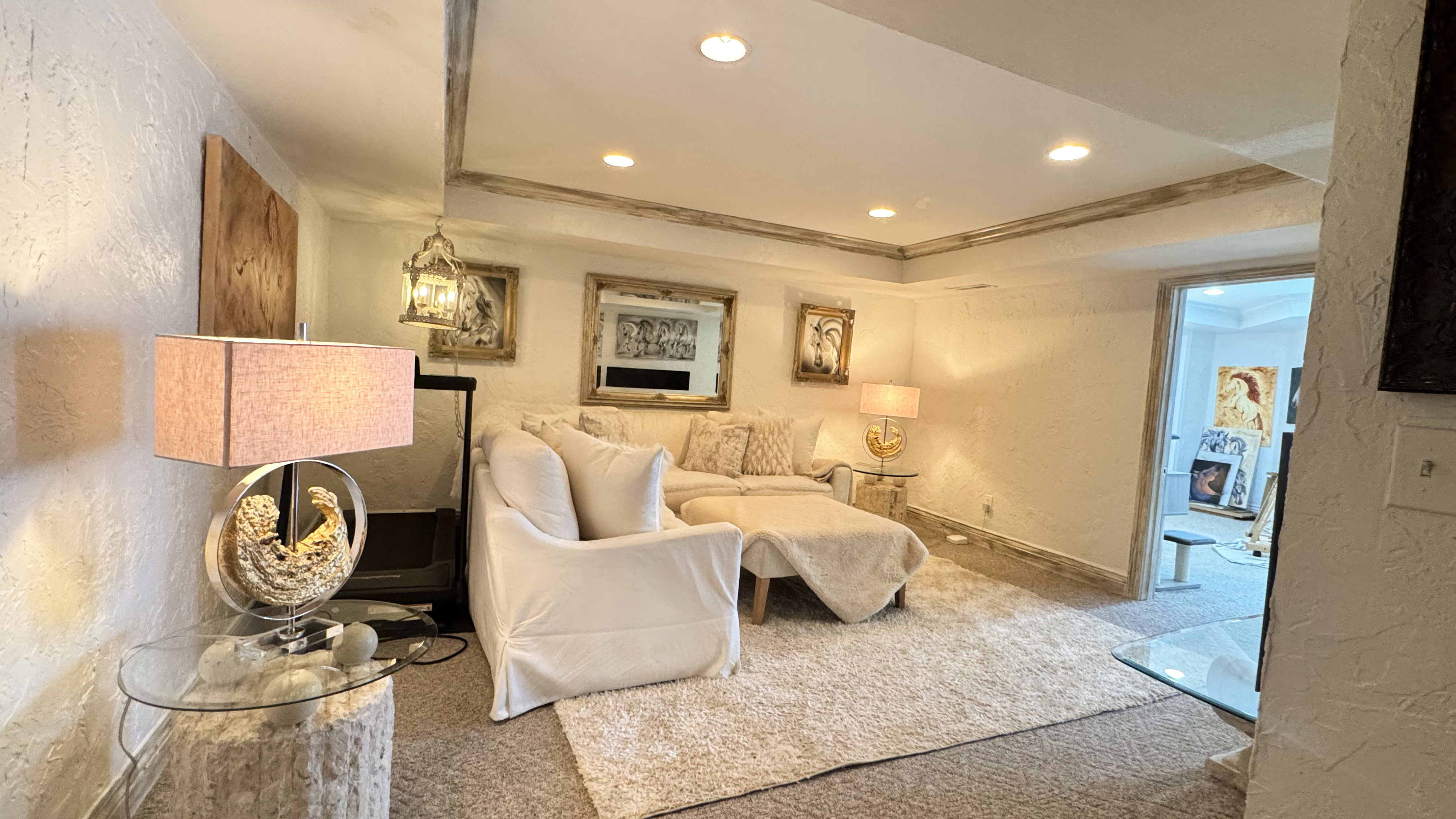 Recessed lighting illuminates this room, featuring textured white walls and a light-toned, plush carpet