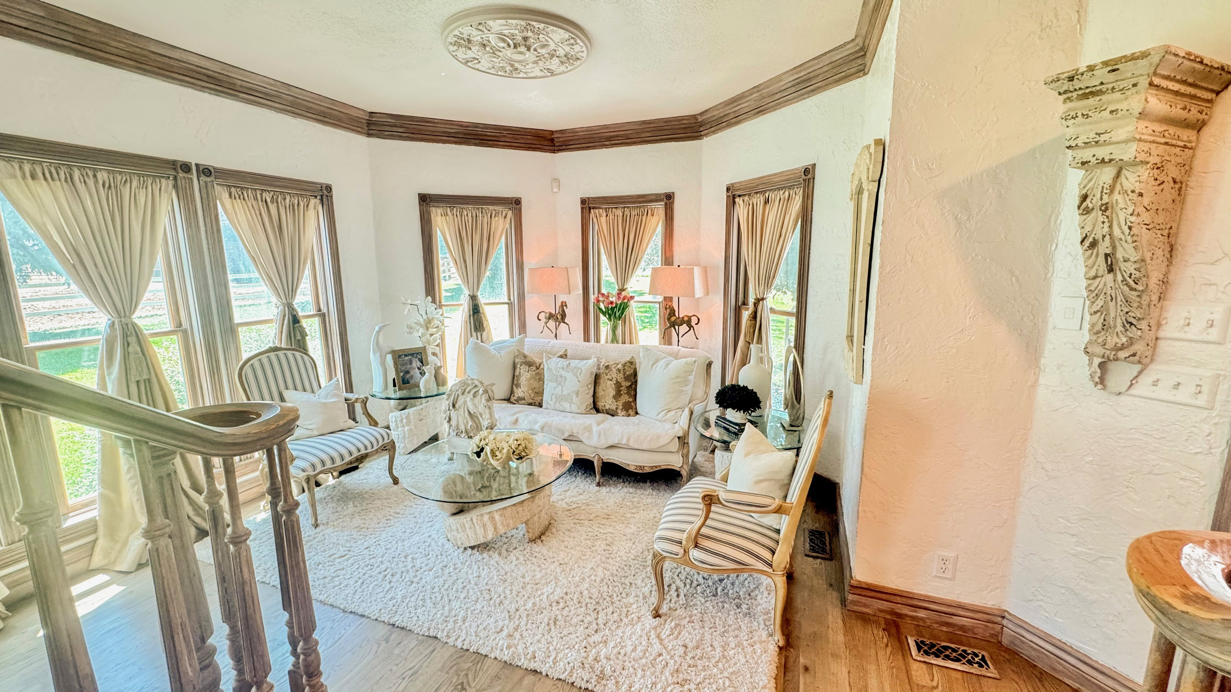 Bright living space with wood-finish flooring, featuring a decorative ceiling medallion and ornate wood trim