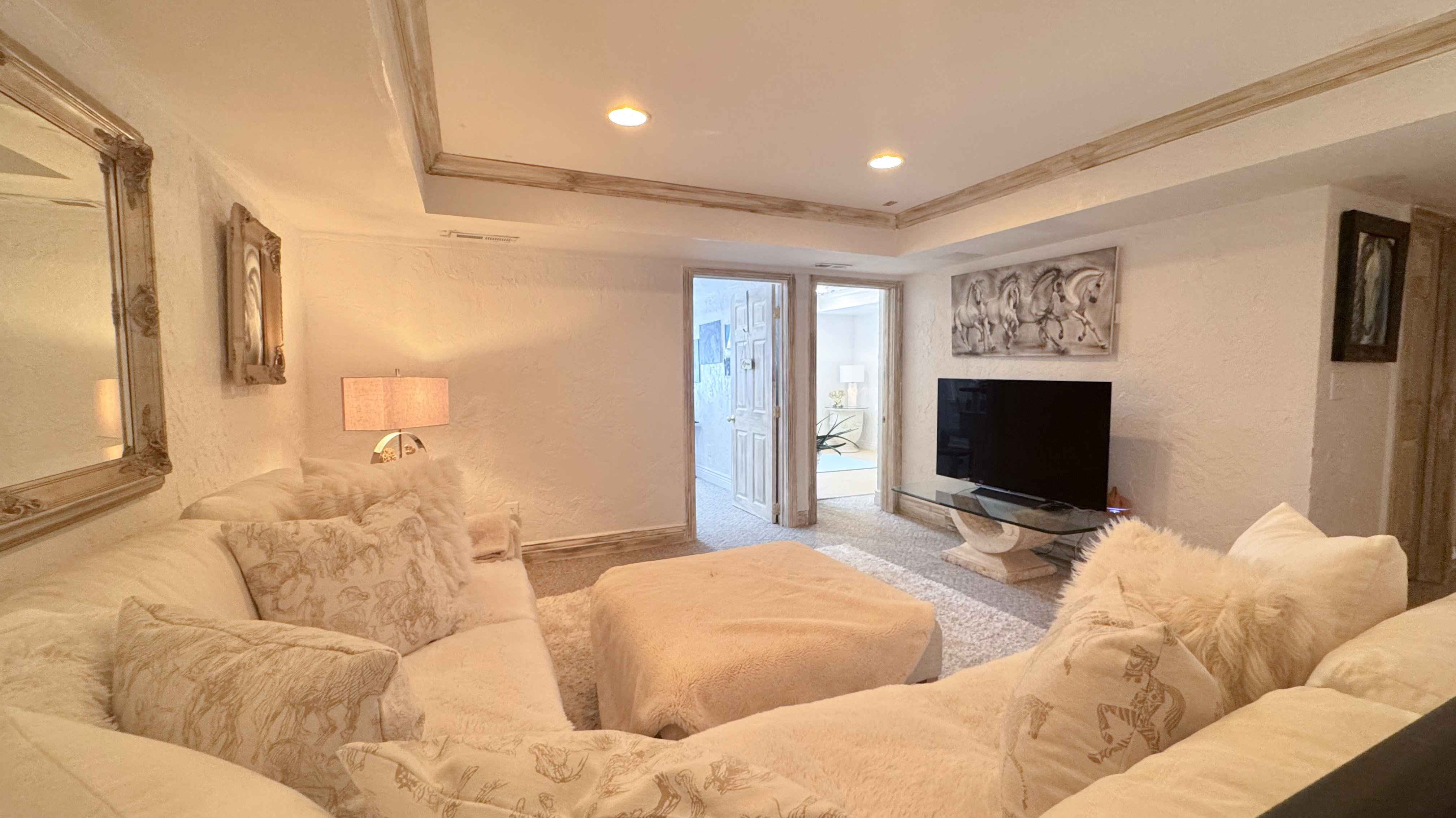 Recessed lighting illuminates this interior space featuring textured white walls and light-toned carpeting