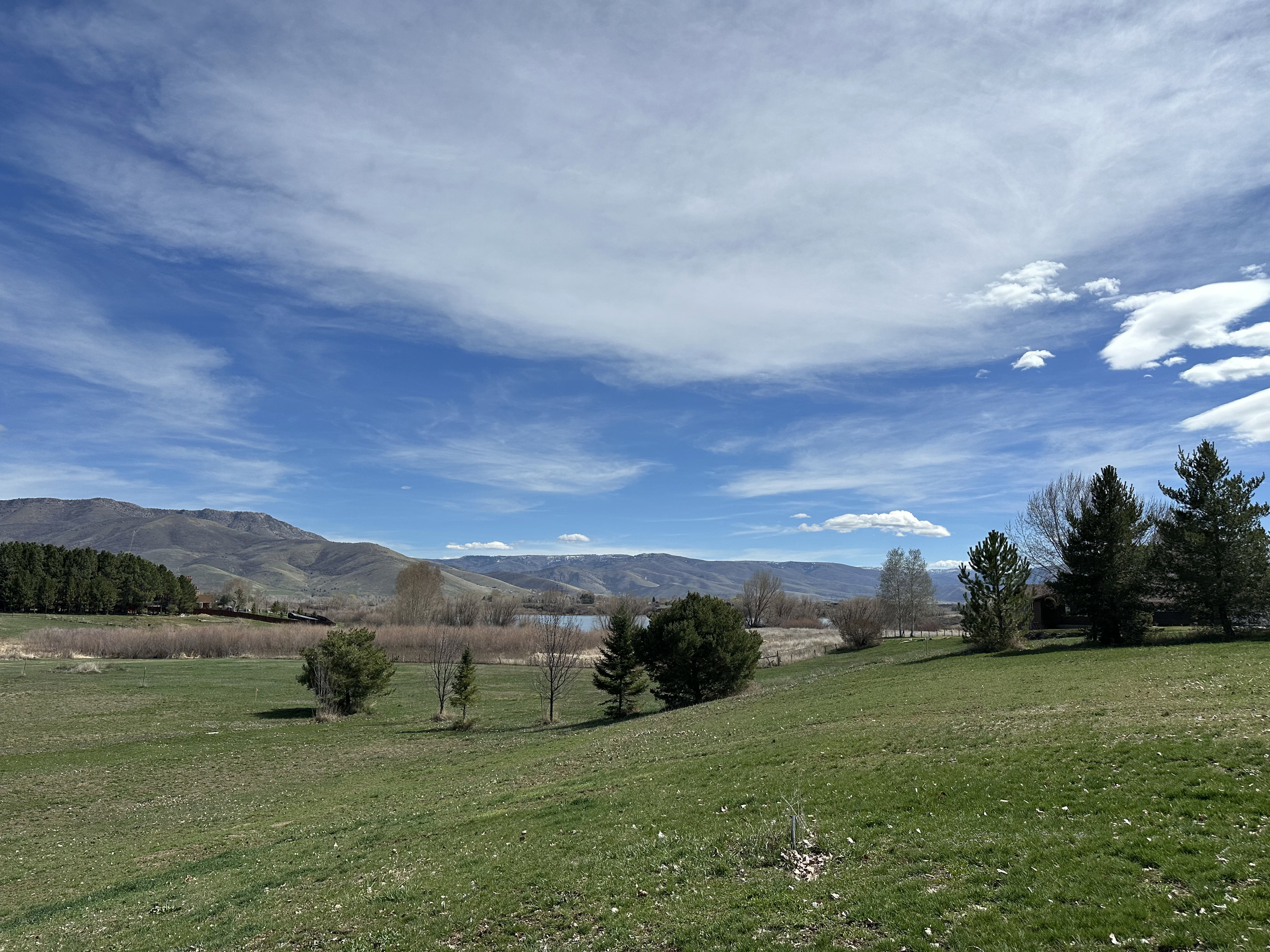 Expansive green lawn sloping towards a body of water, bordered by distant mountains