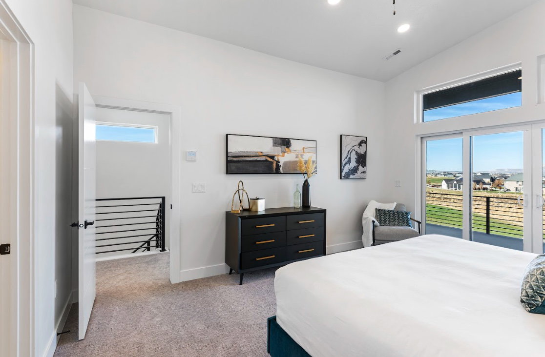 Bright interior space featuring a sliding glass door to a balcony, a high transom window, vaulted ceiling, recessed lighting, and carpeted flooring