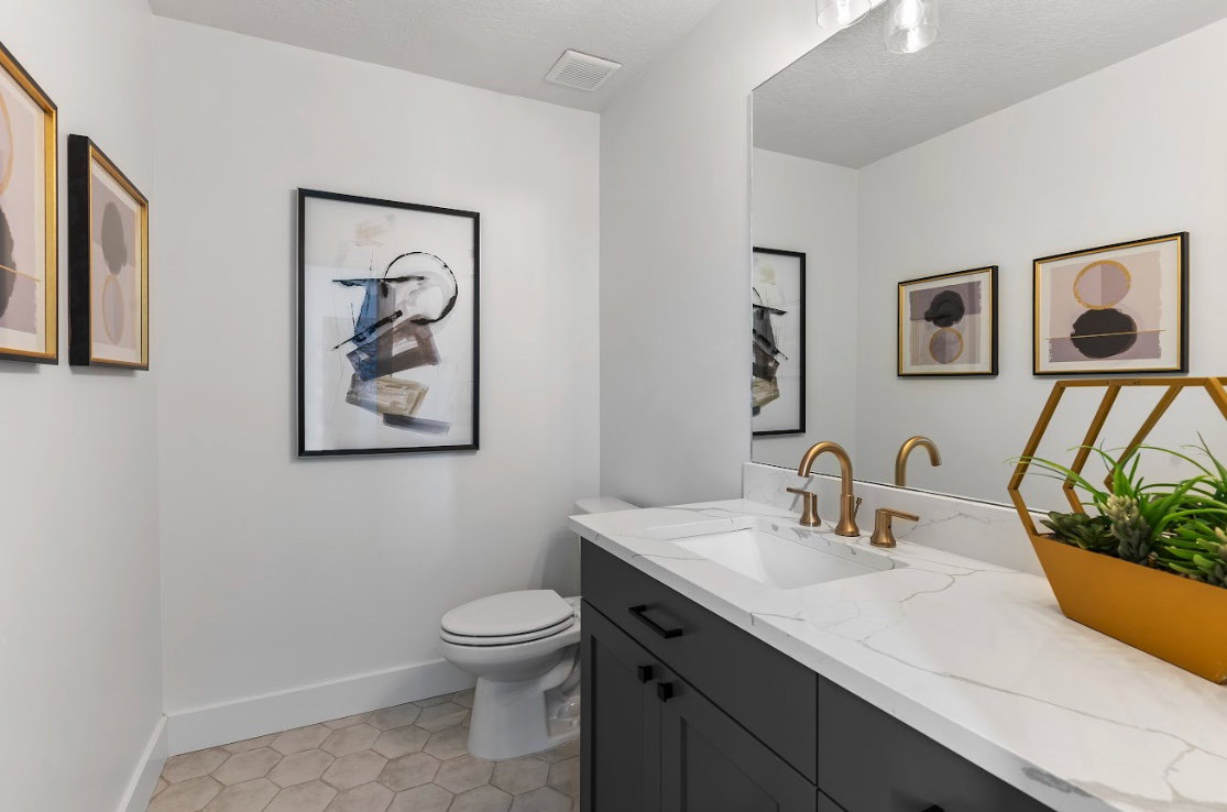 Vanity featuring a white countertop with subtle veining, undermount sink, and brass-tone fixtures
