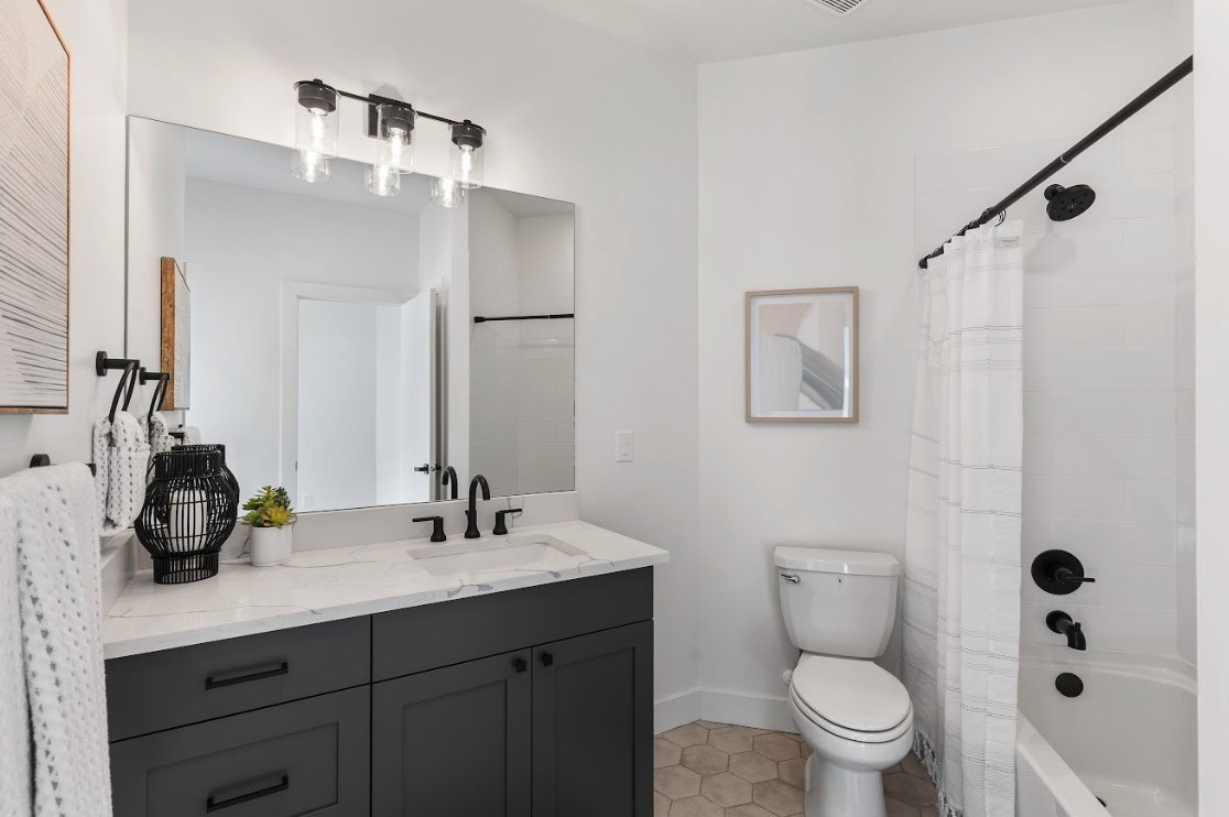 Bathroom featuring a dark gray vanity with a light countertop, an undermount sink, and a large mirror
