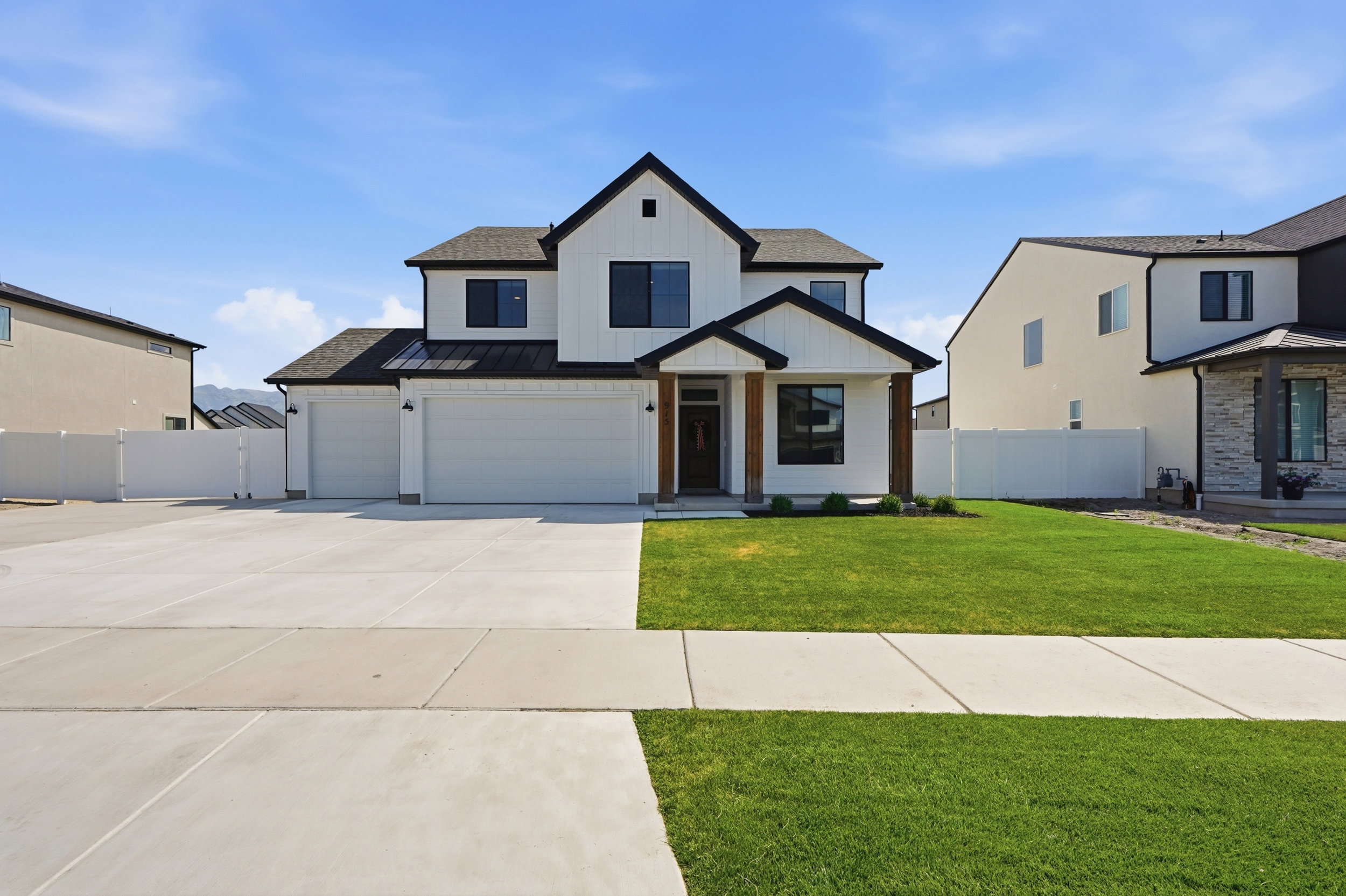 Modern farmhouse exterior featuring white vertical siding, black-framed windows, and a black shingle roof