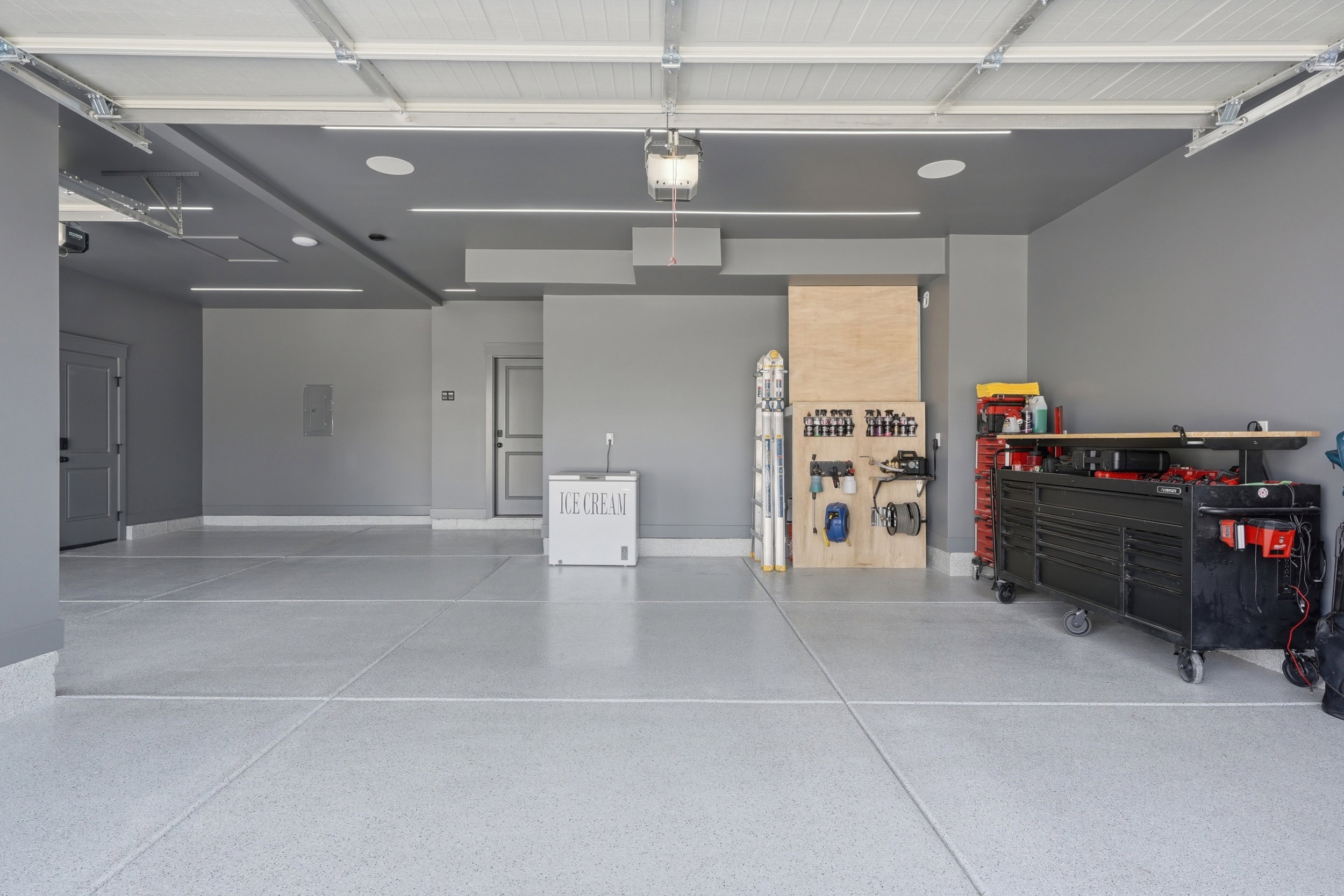 Spacious garage featuring a light gray epoxy floor coating, recessed lighting, and access doors