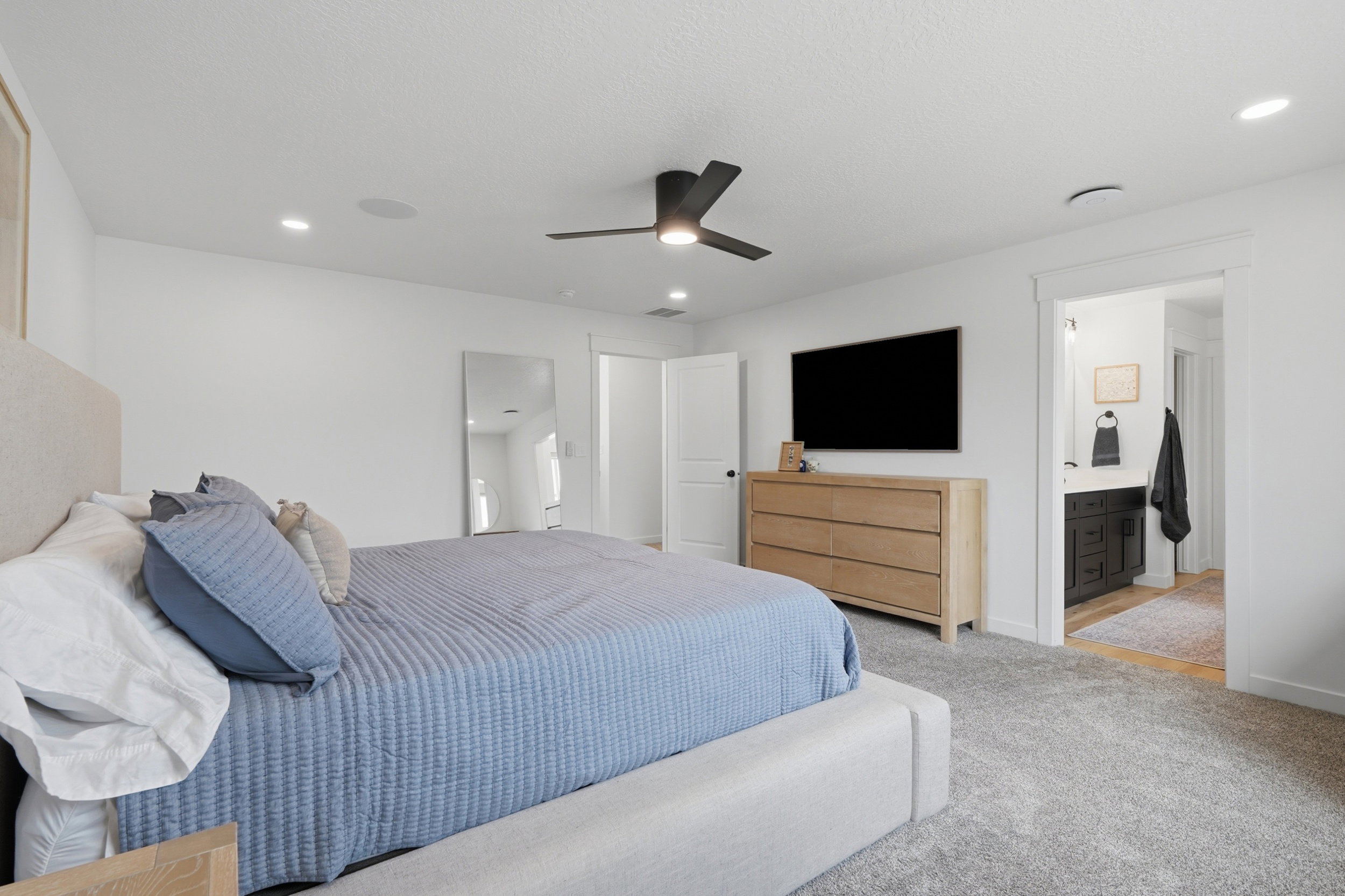 Spacious bedroom featuring recessed lighting, a ceiling fan, light gray carpeting, and a built-in wall speaker