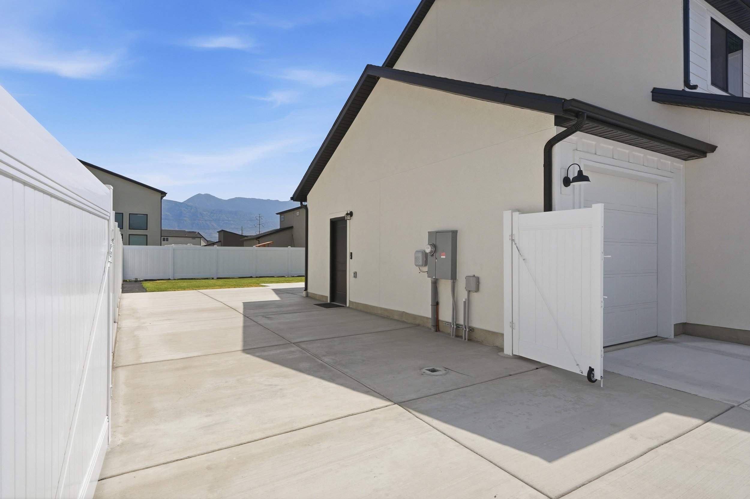 Concrete driveway with a white privacy fence and a single-car garage door