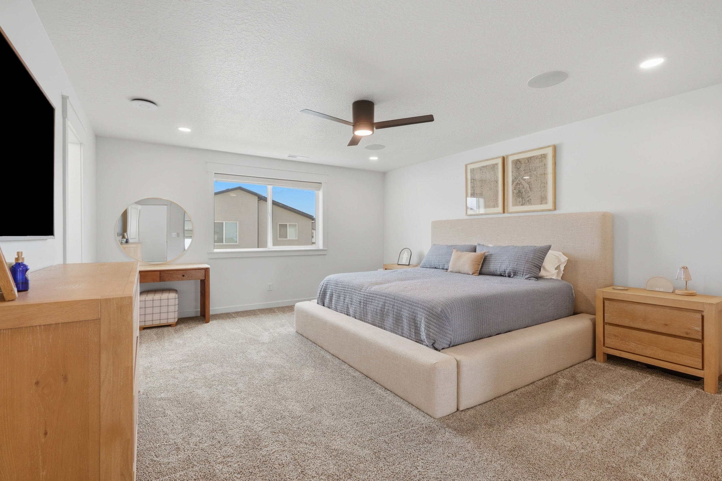 Spacious bedroom featuring neutral carpeting, a large window, a ceiling fan with integrated lighting, recessed lighting, and built-in ceiling speakers