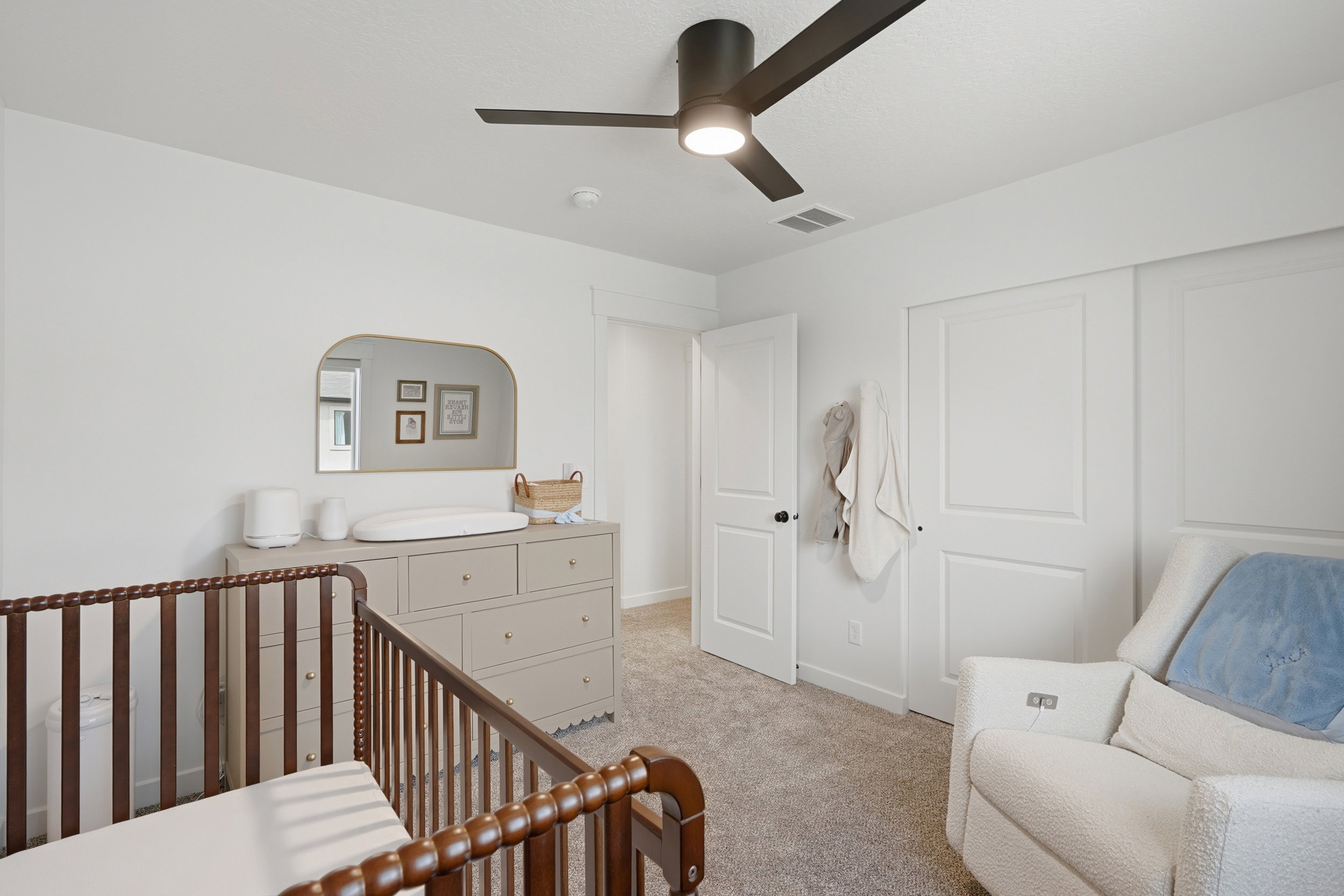 Carpeted room featuring a ceiling fan with integrated lighting, flat-panel closet doors, a white paneled door, and neutral wall tones