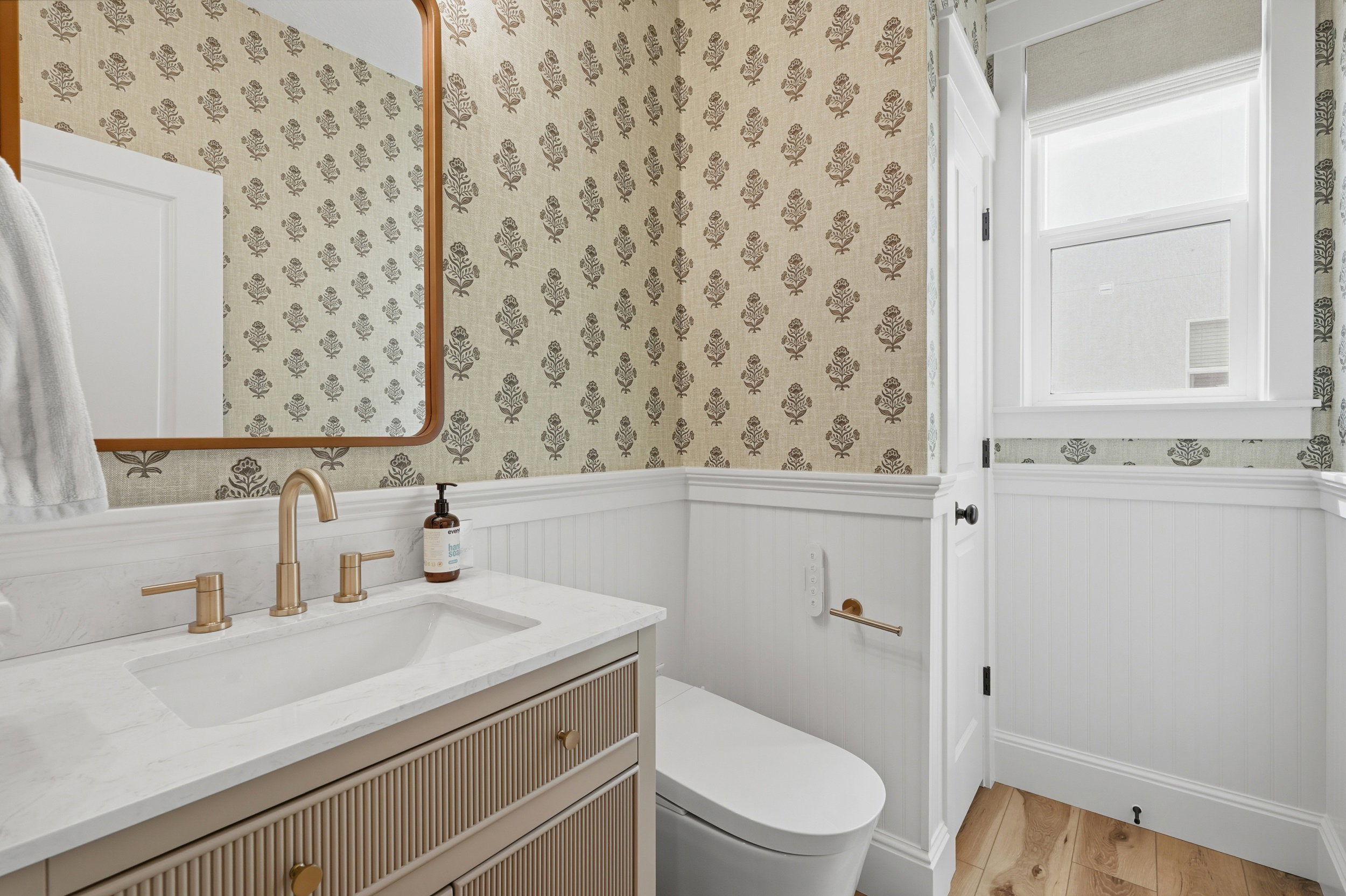 Bathroom featuring a white vanity with a light countertop, gold-tone fixtures, and a rectangular mirror