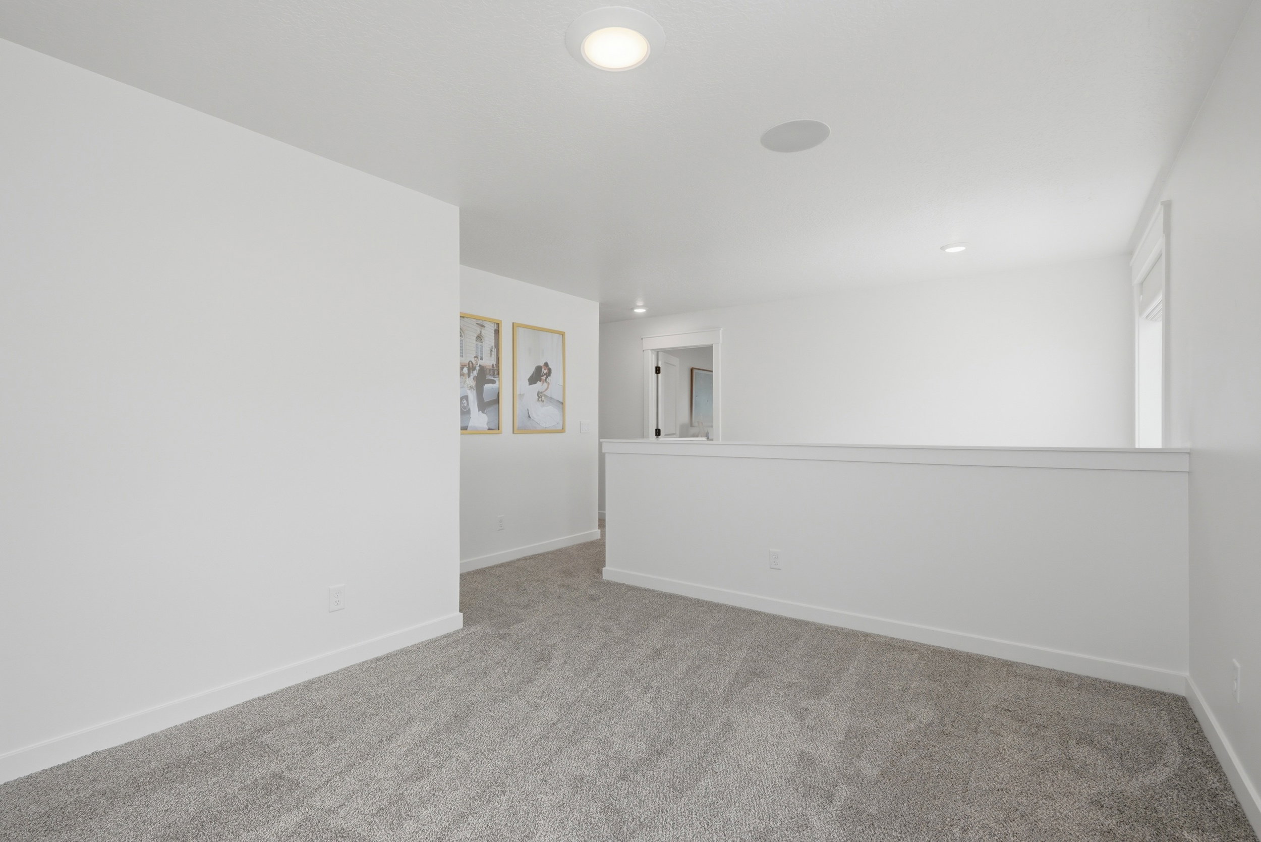Carpeted upstairs landing featuring a partial wall, white trim, recessed lighting, and a built-in ceiling speaker