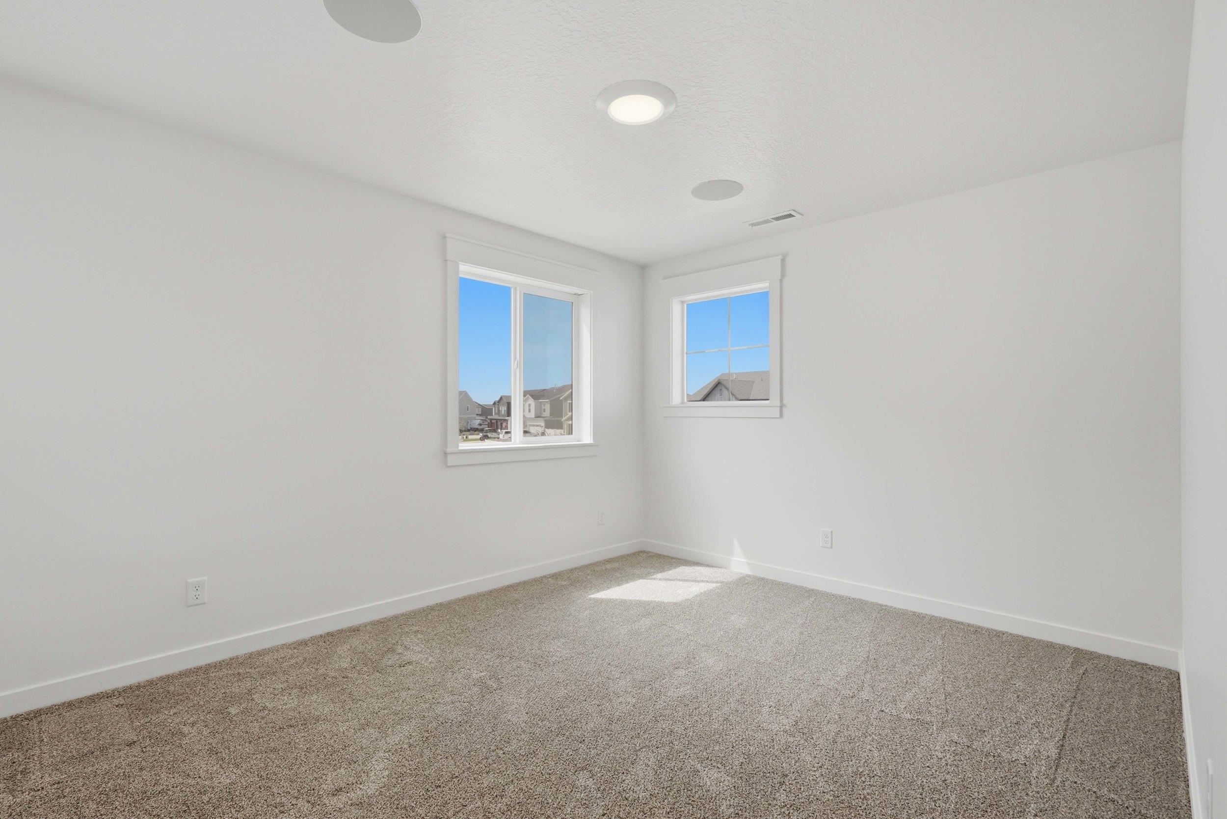 Carpeted room with white walls, dual windows, and recessed lighting