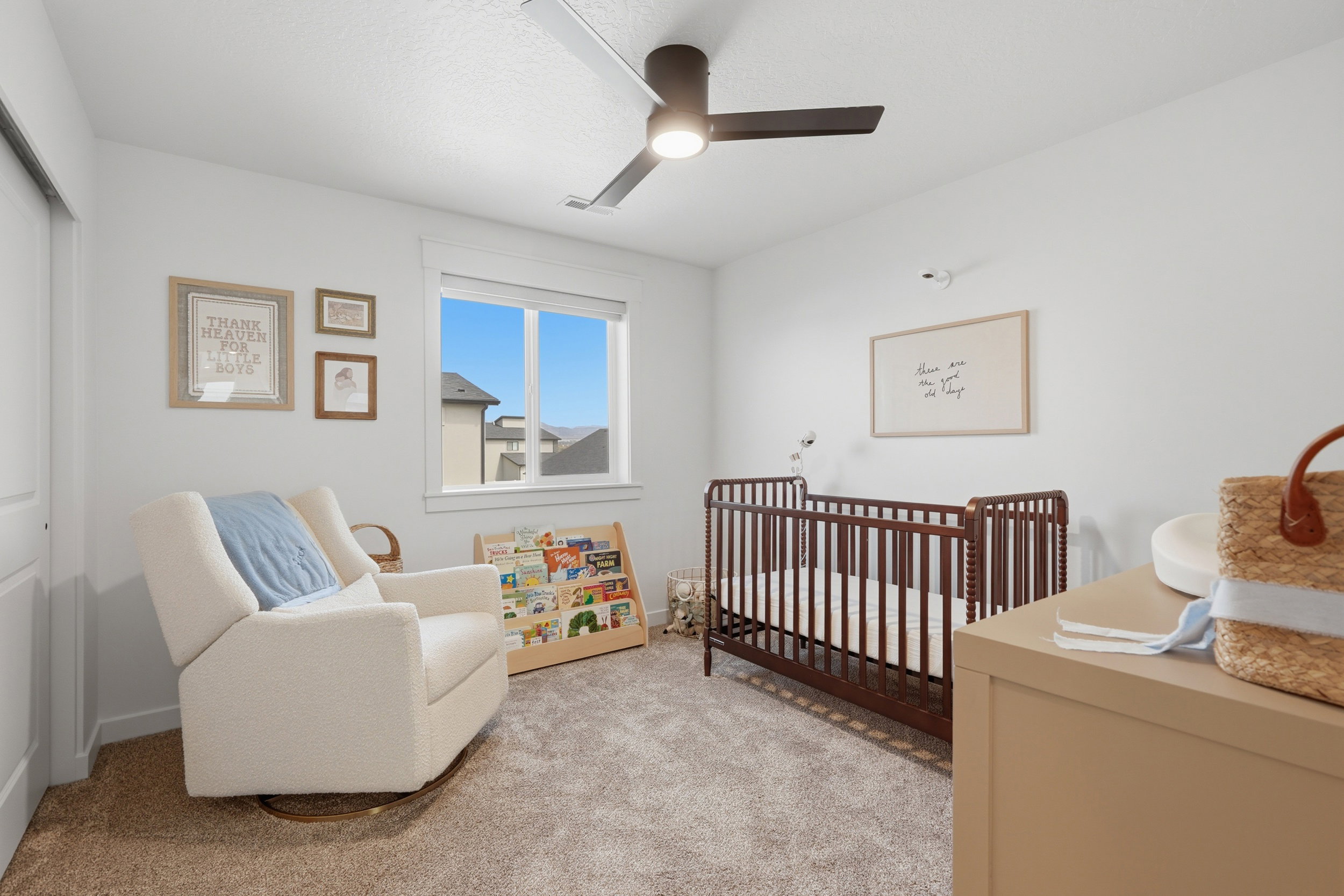 Neutral-toned room featuring a single window, a dark-toned ceiling fan, and light-toned carpeting