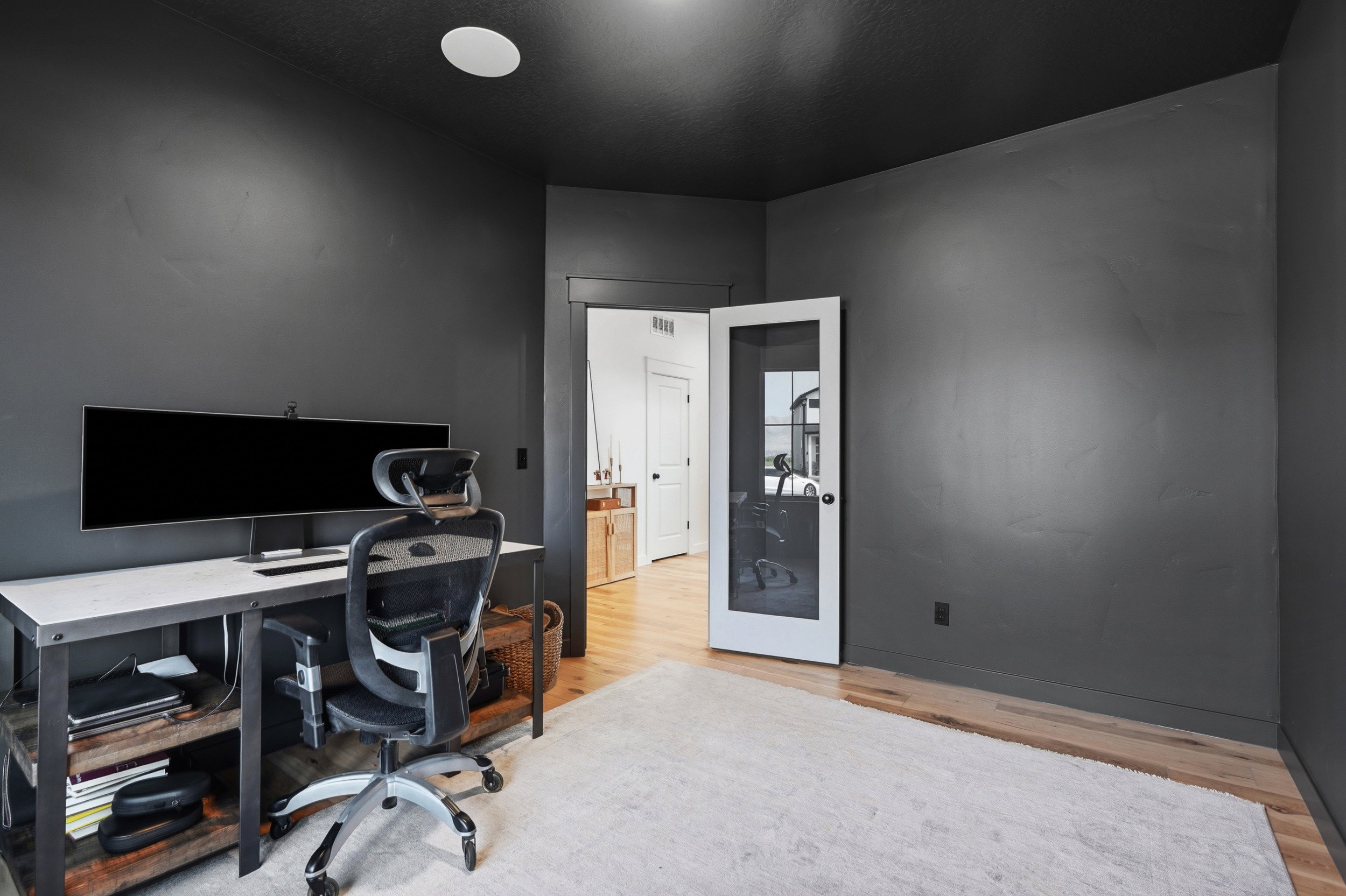 Dedicated room featuring dark painted walls and ceiling, a recessed ceiling light, a glass-paneled interior door, and wood-finish flooring
