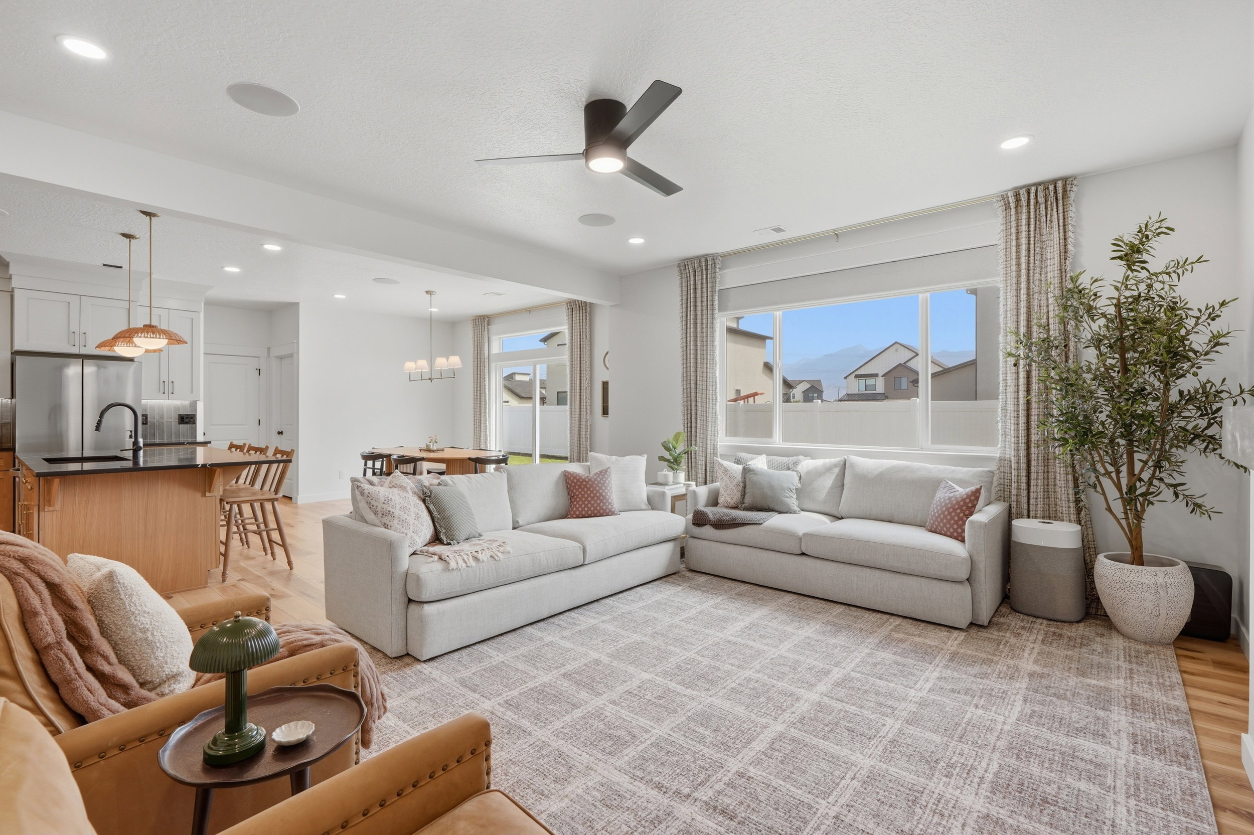 Spacious living area featuring light wood-finish flooring and a contemporary ceiling fan