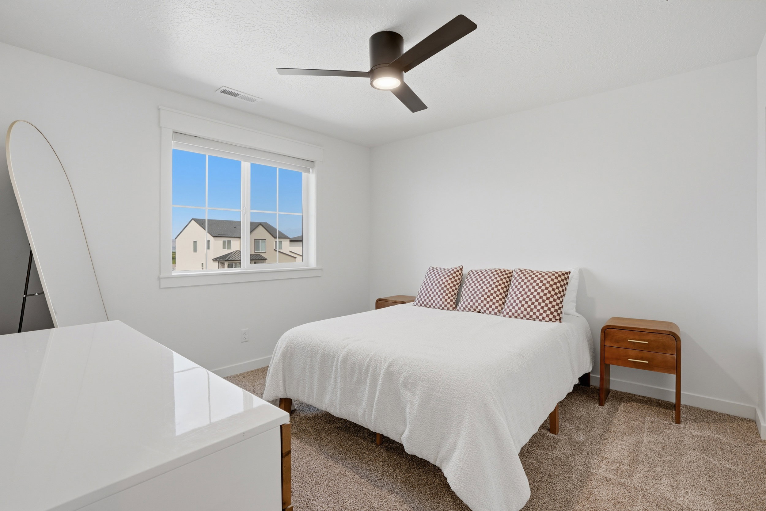 Bright interior space featuring a window with white trim, a ceiling fan with integrated lighting, and neutral-toned carpet flooring