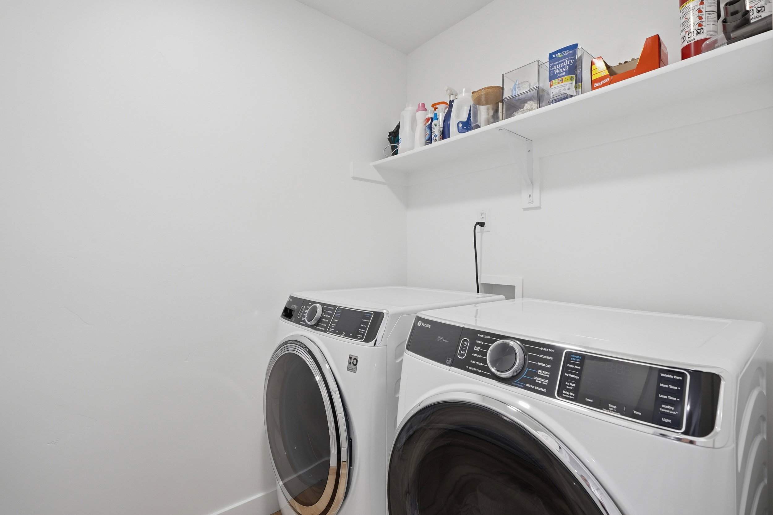 Dedicated laundry area featuring white walls, baseboards, and a single floating shelf