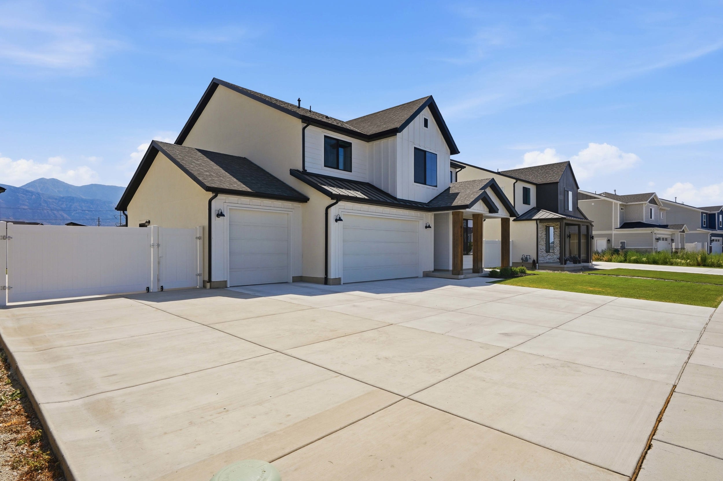 Modern two-story residence featuring a two-car garage, white vertical siding accents, and a dark shingle roof