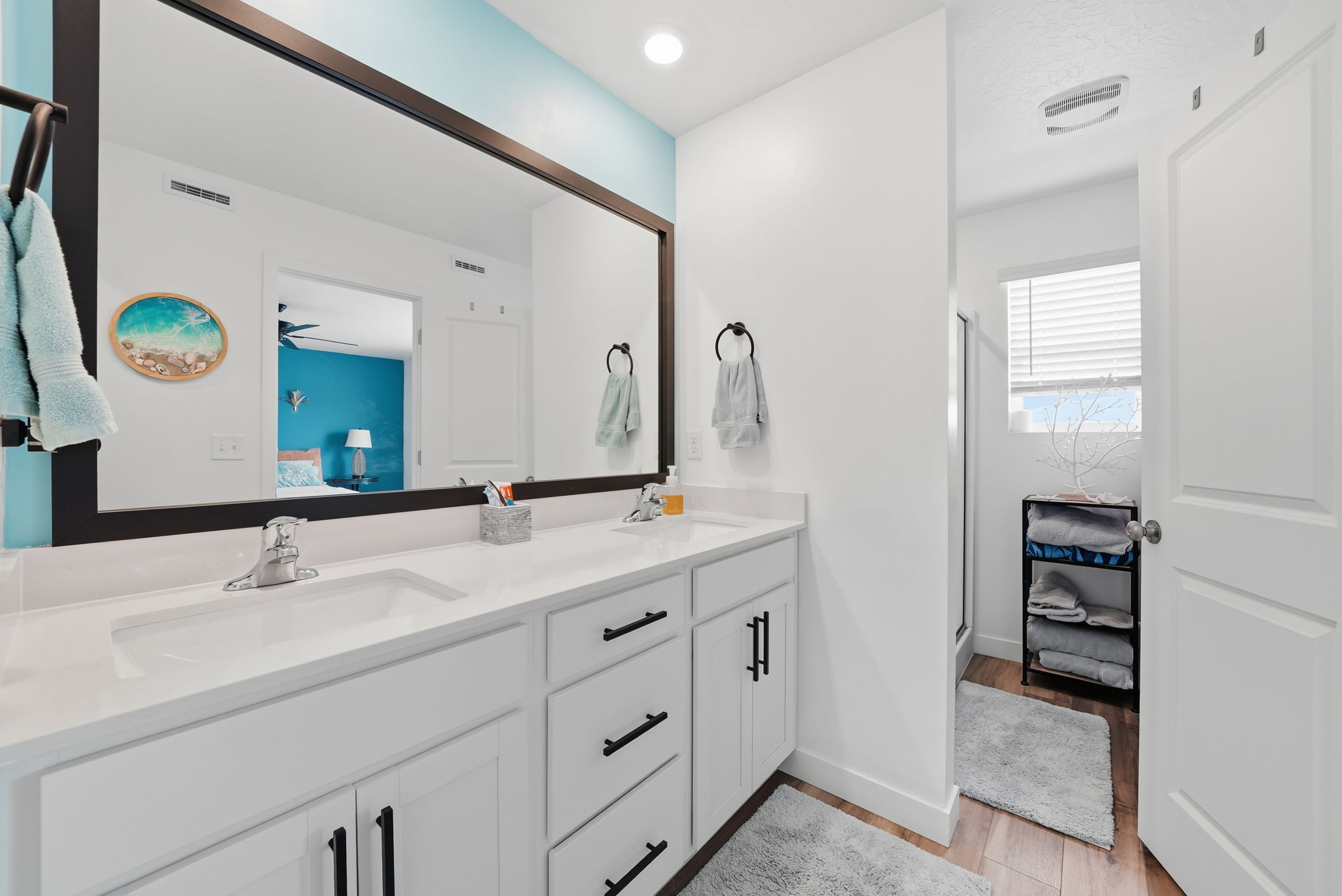 Dual vanity with white cabinetry and black hardware, set under a large framed mirror