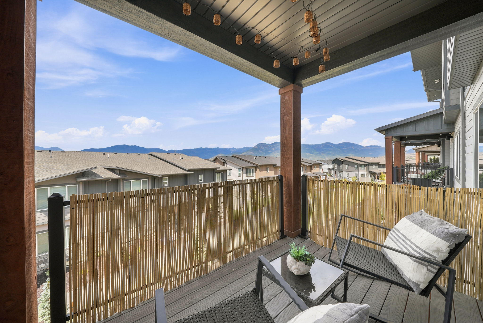 Covered outdoor deck with composite decking, a bamboo-style screen, and mountain scenery
