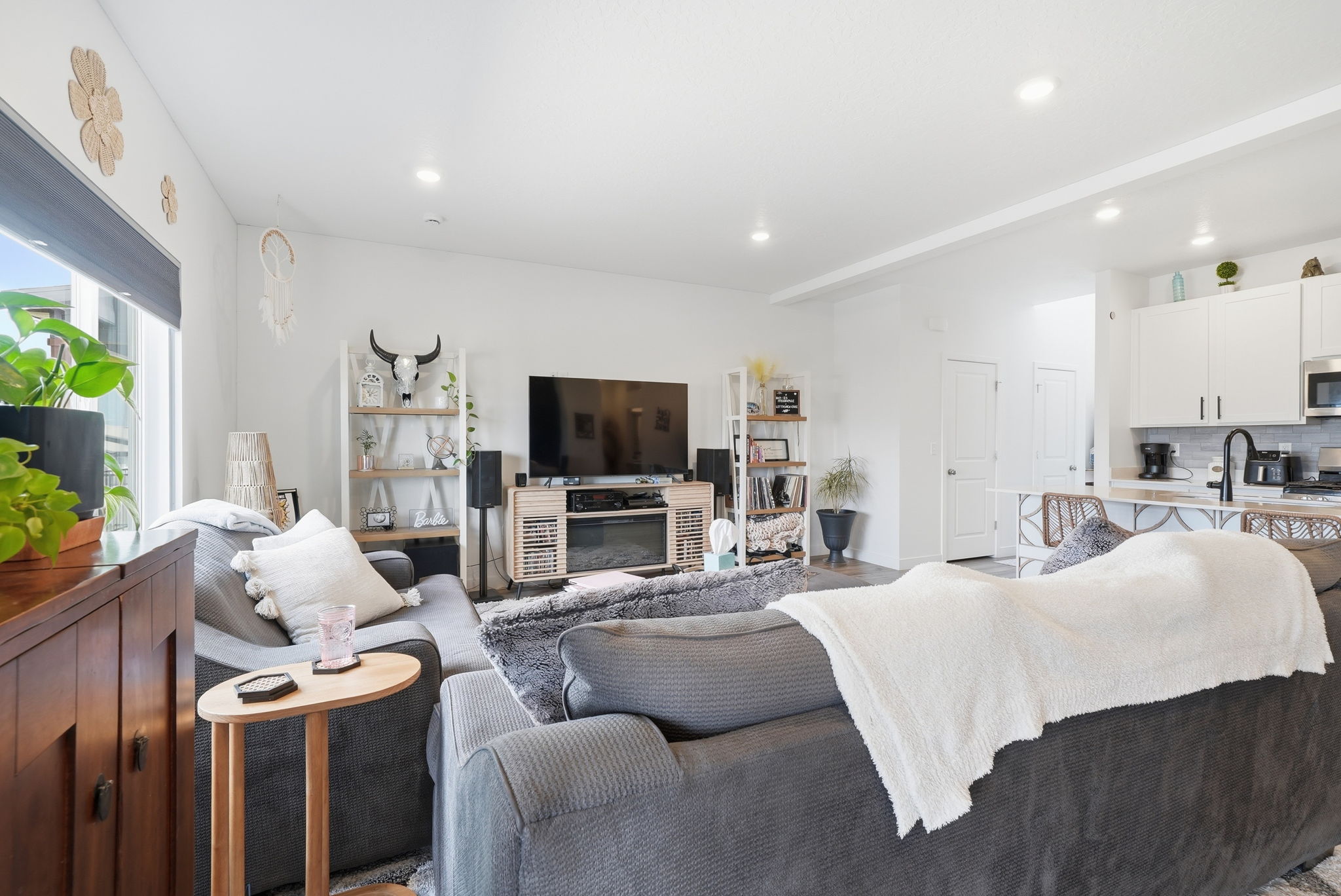 Open-concept living area featuring high ceilings, recessed lighting, and a large window with roller shades