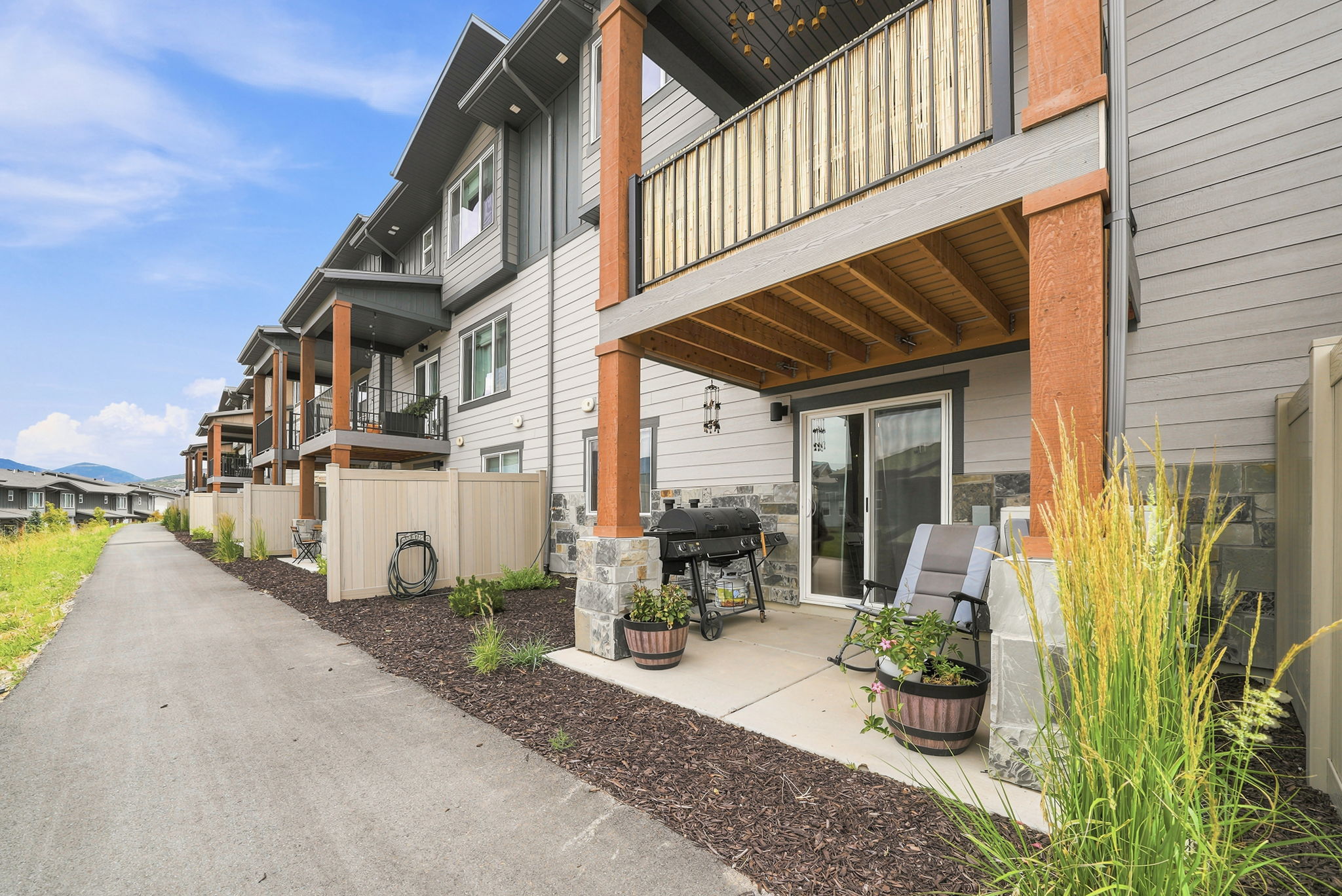 Patio area featuring a sliding glass door entry, stone veneer siding, and wood-finish support columns