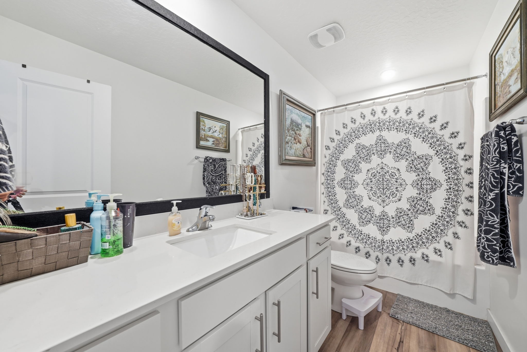 Bathroom vanity with a single basin sink, white countertop, and white cabinetry