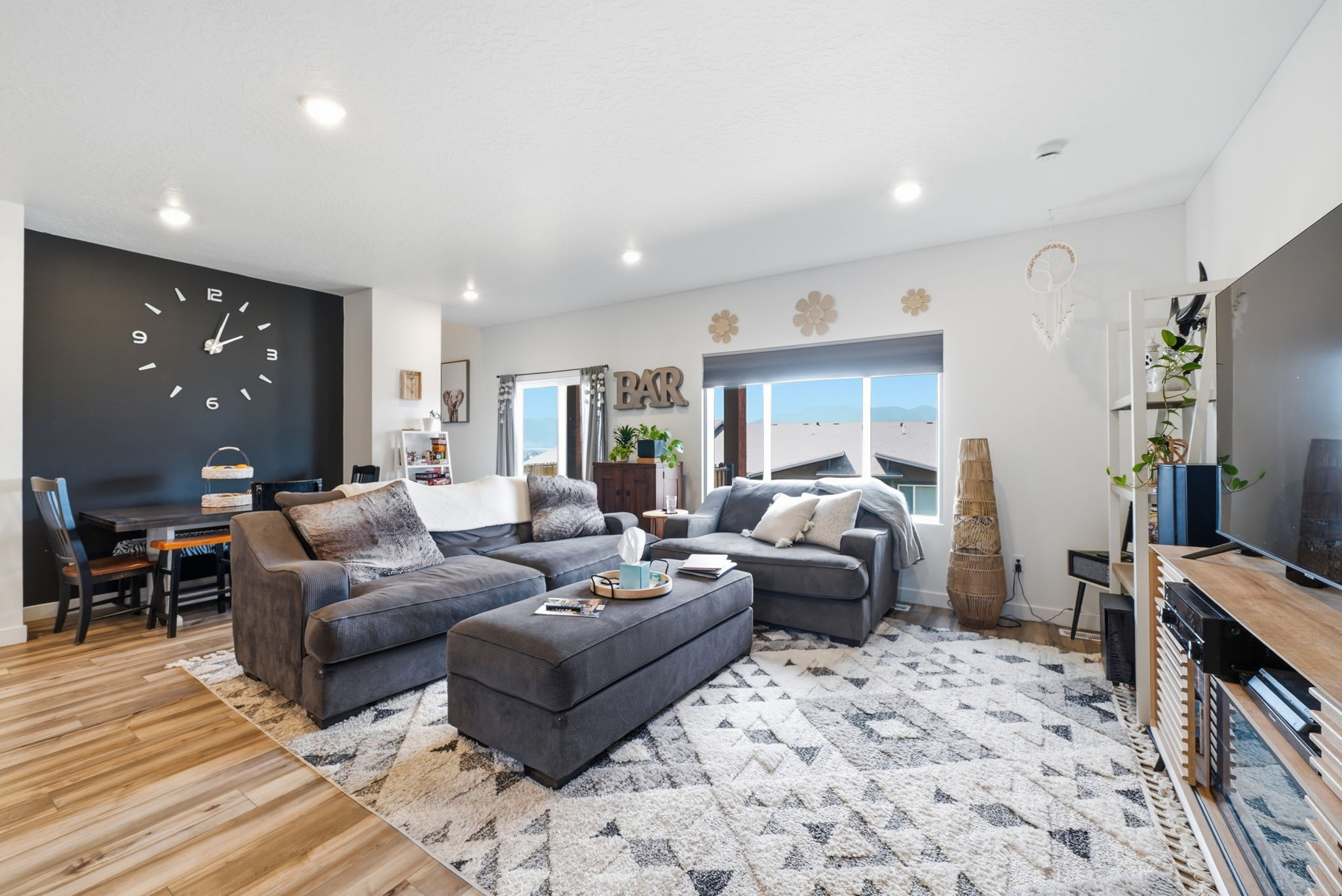 Open-concept living area with wood-finish flooring, recessed lighting, and a large window