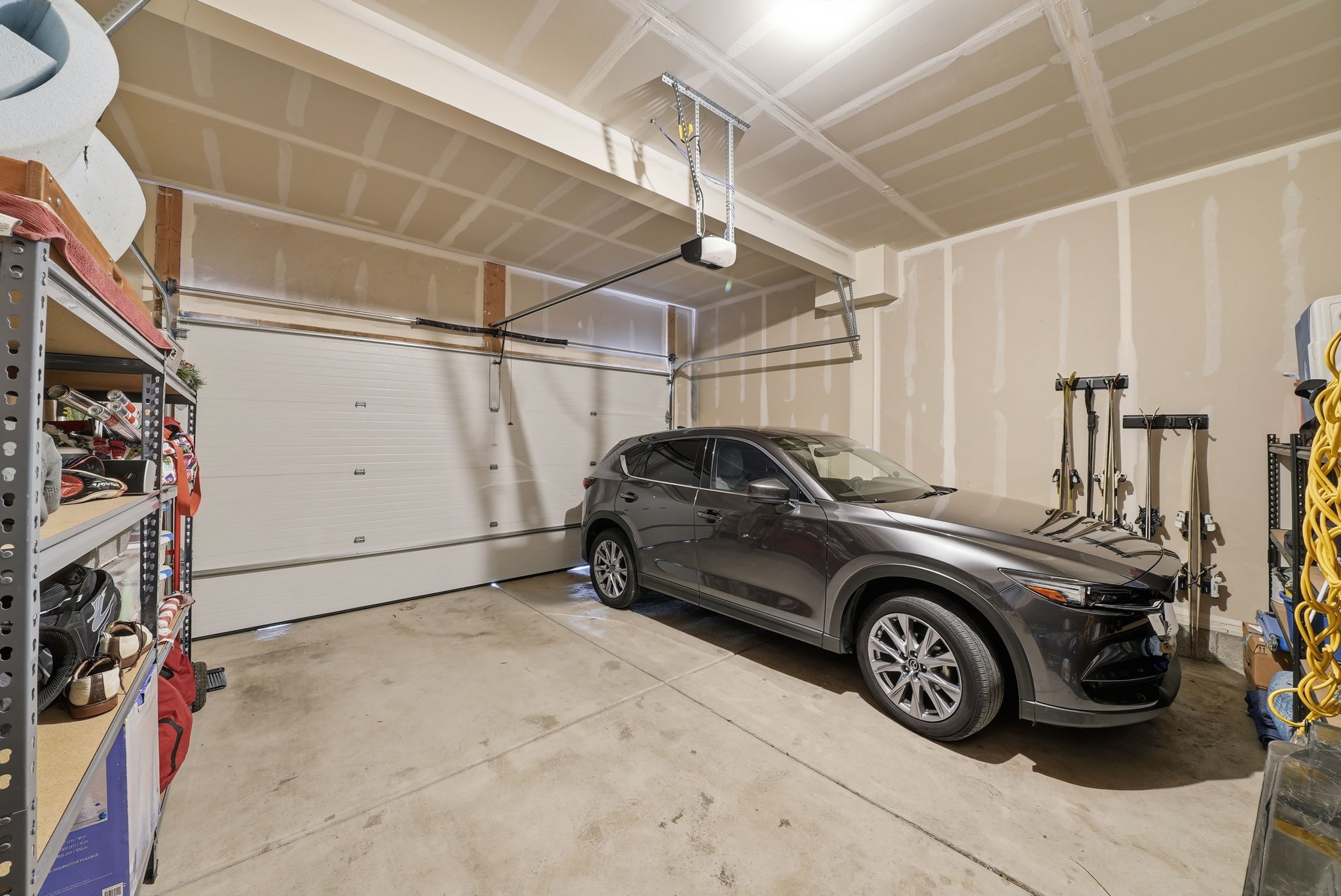 Spacious garage with a sectional overhead door, exposed wood rafters, and a concrete floor