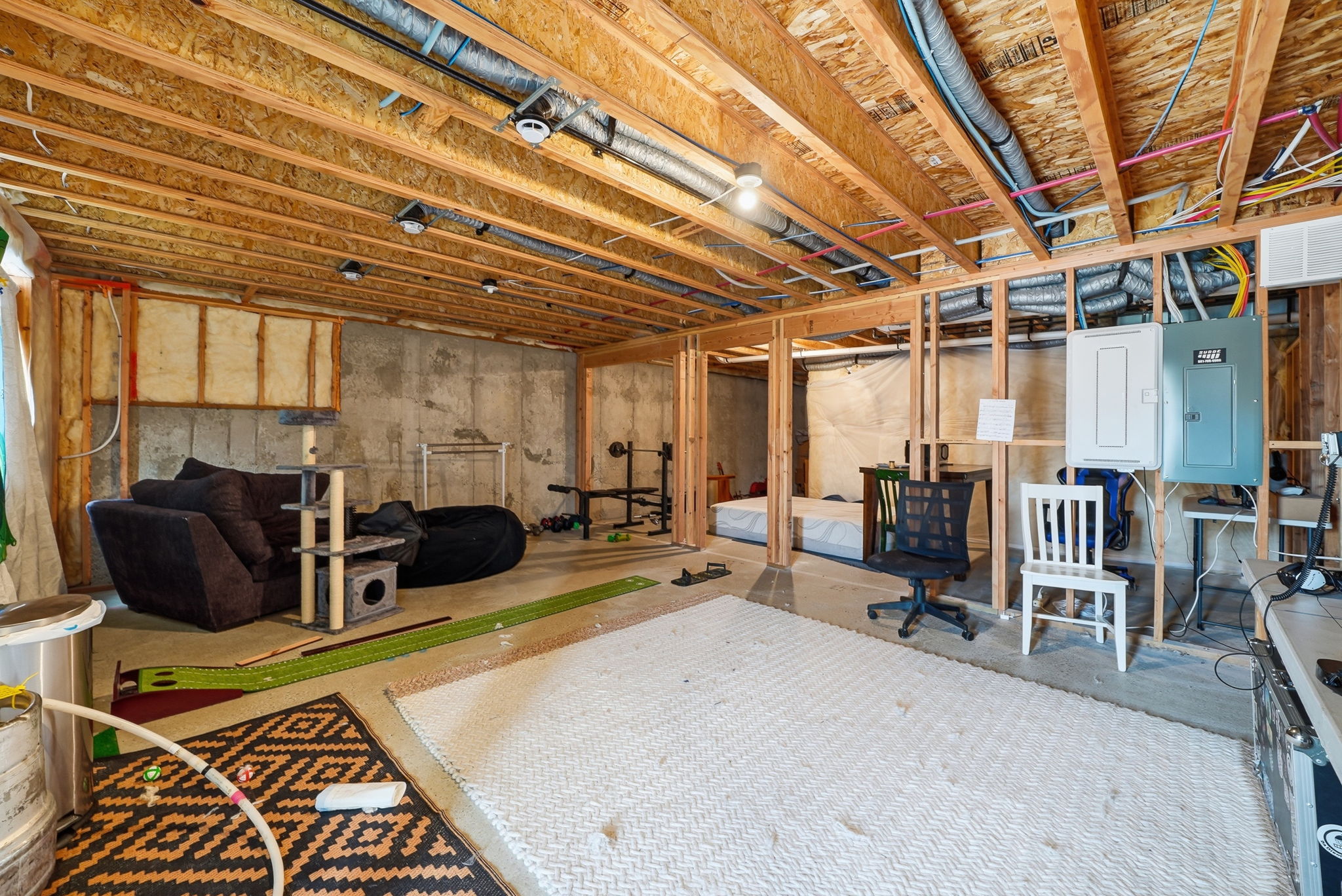 Unfinished basement featuring exposed wood joists and concrete walls, ready for personalized customization