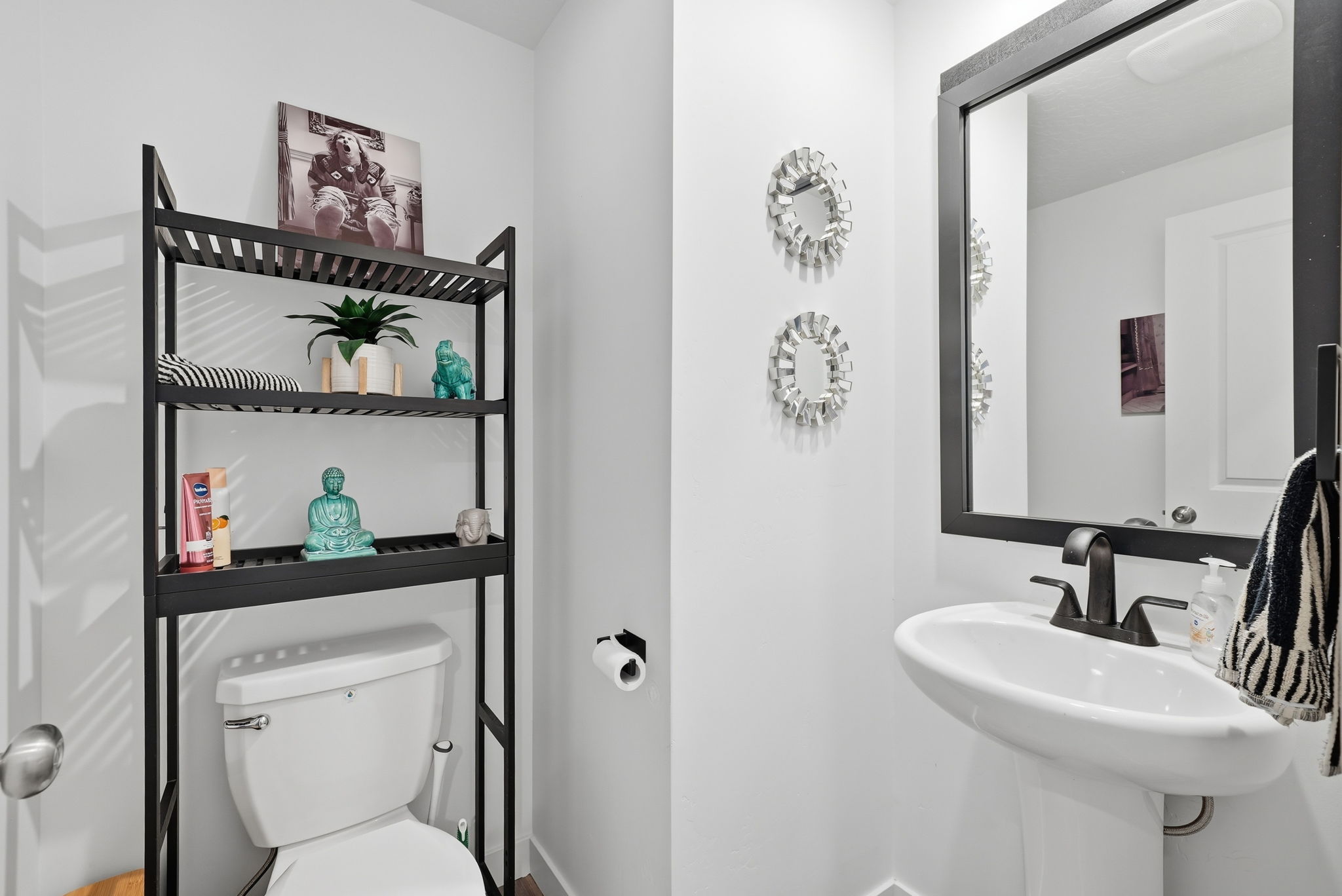 Pedestal sink featuring a black-framed mirror, matte black faucet, and white walls
