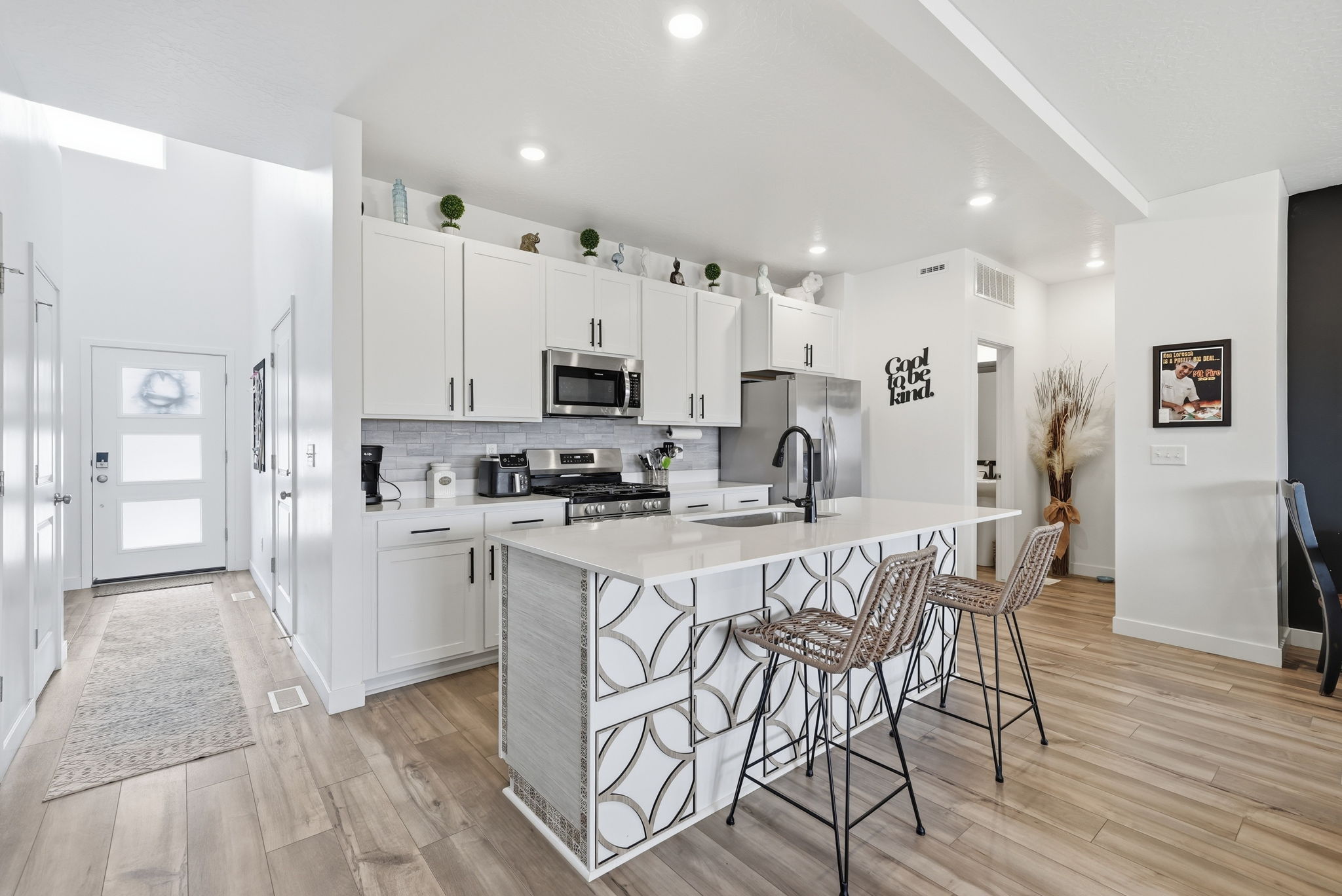 Modern kitchen featuring white cabinetry, stainless steel appliances, and a central island with decorative paneling