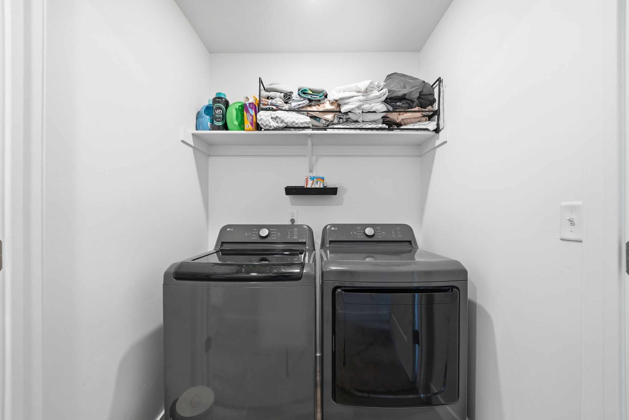 Dedicated laundry area featuring a built-in white shelf and overhead wire shelving