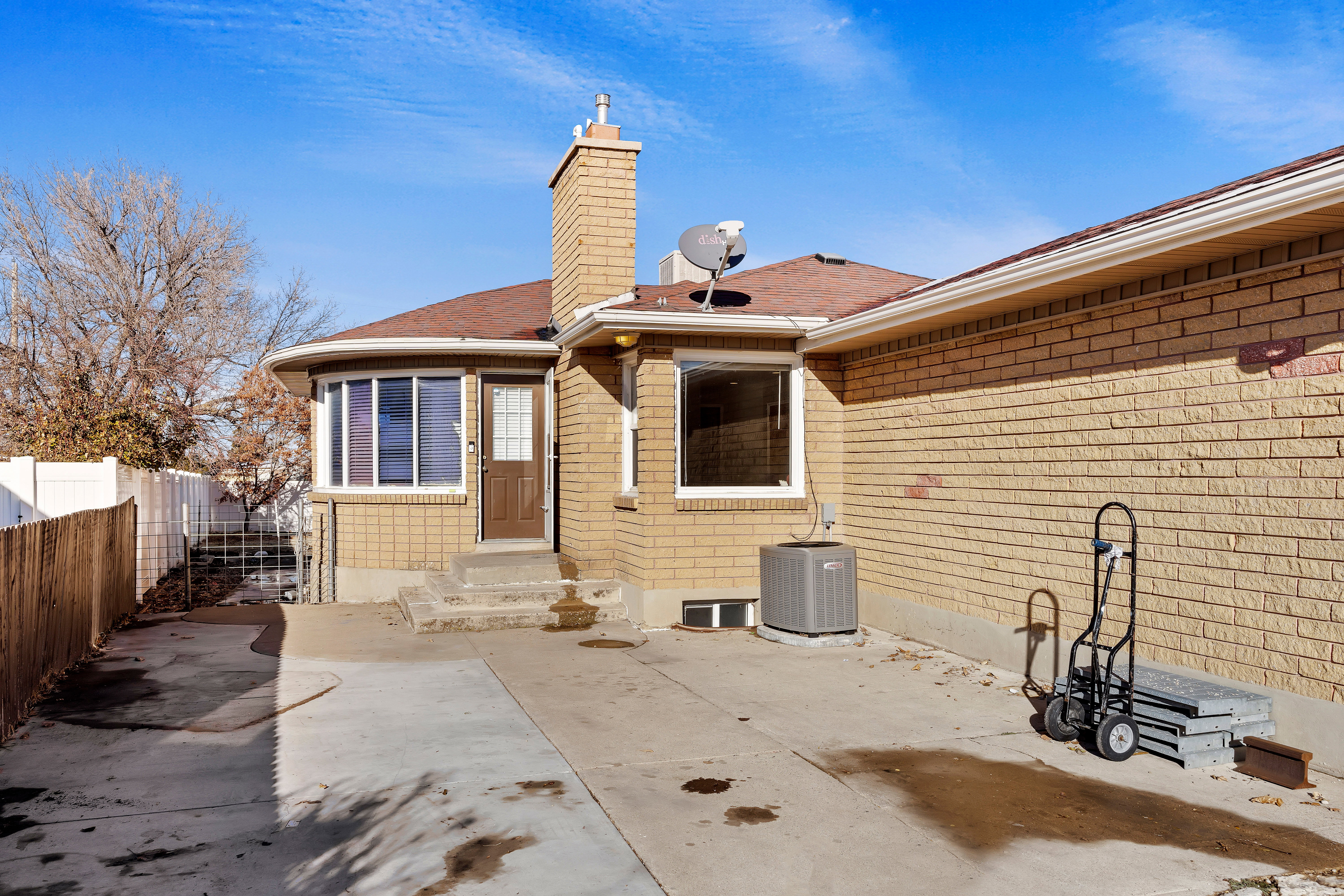 Brick exterior featuring a bay window, a brown entry door, and a prominent chimney structure