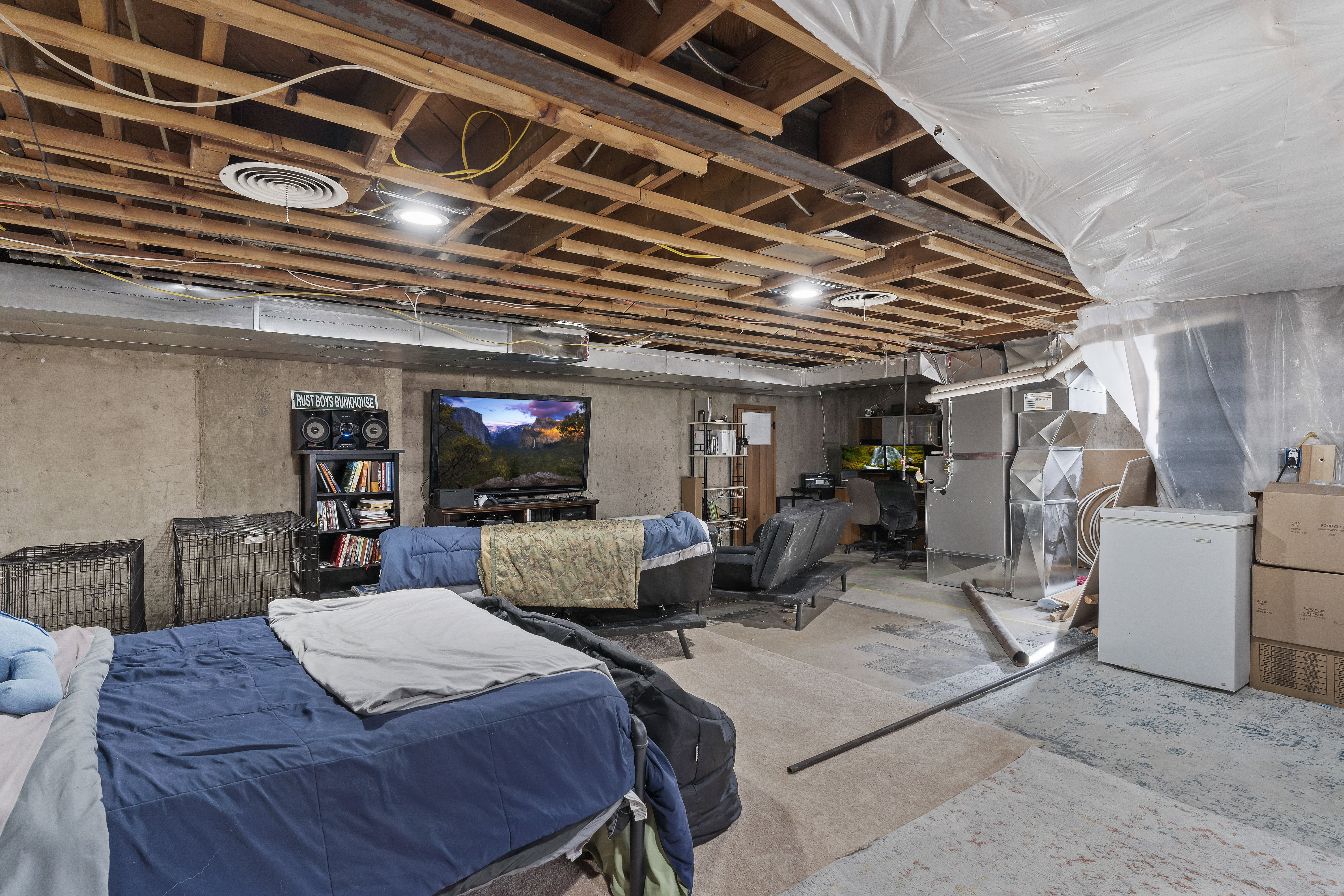 Unfinished basement featuring exposed wood joists, concrete walls, and visible ductwork