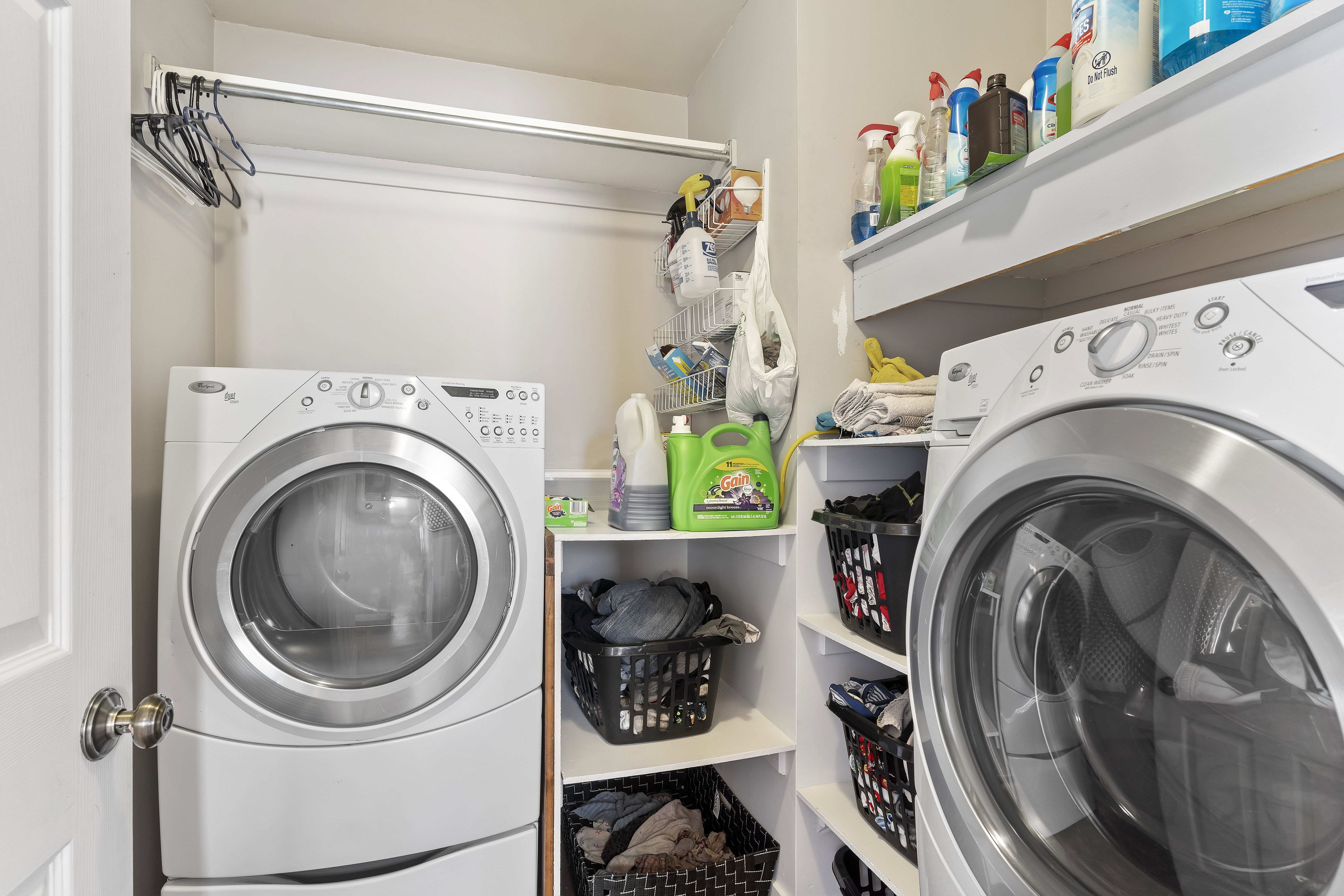 Dedicated laundry area featuring a front-loading washer and dryer, built-in shelving, and a hanging rod