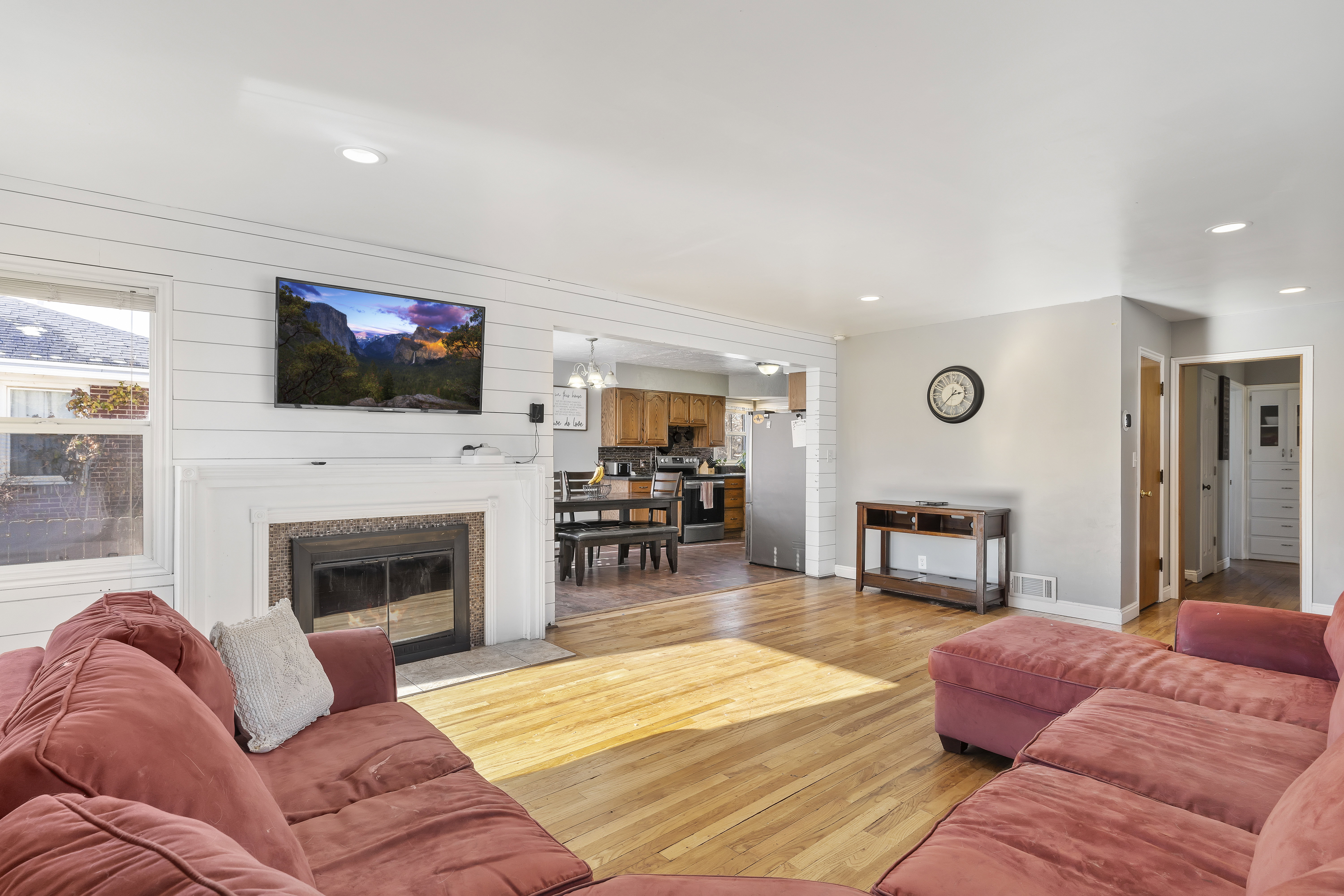 Living area featuring wood-finish flooring, recessed lighting, and a white shiplap accent wall
