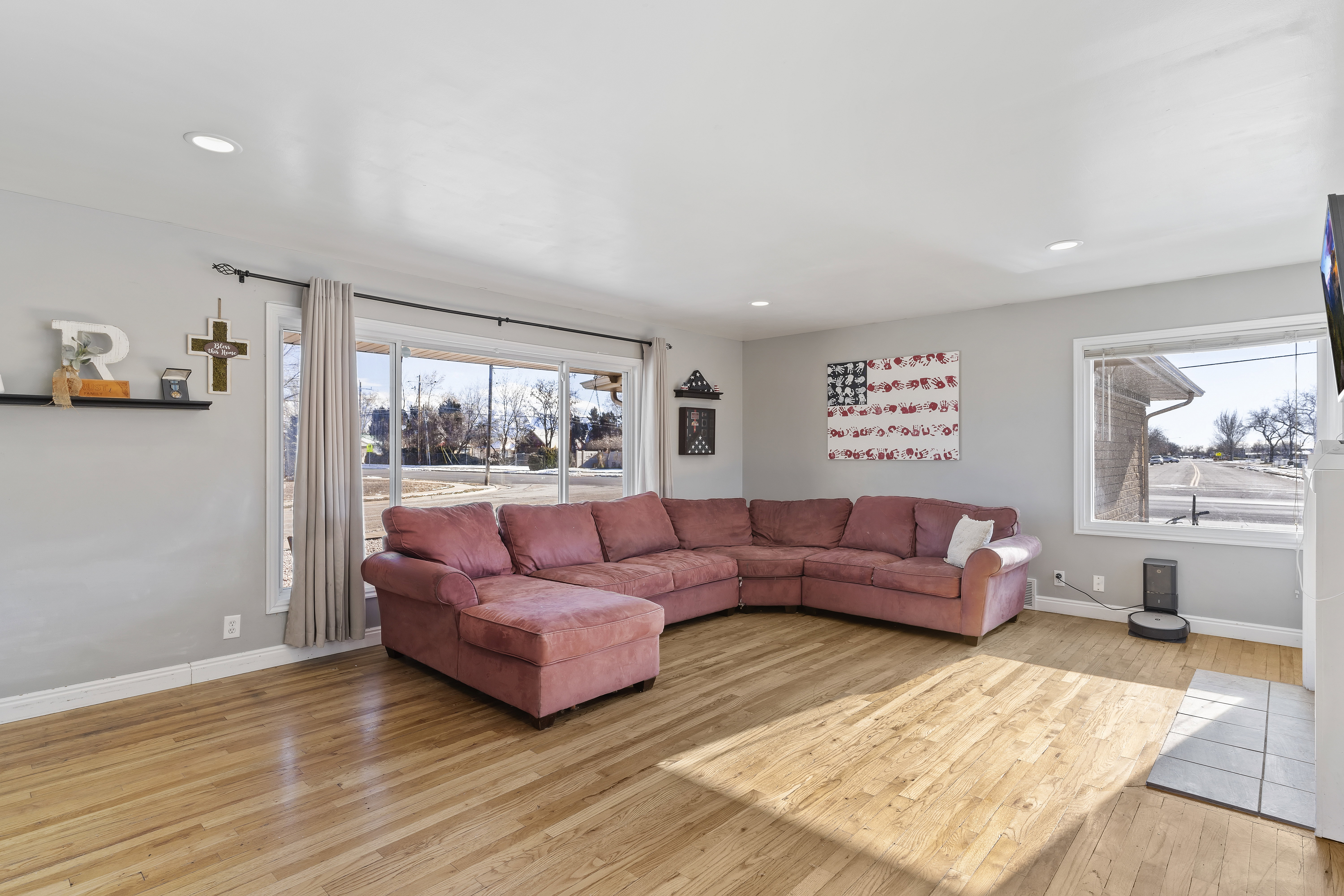 Spacious living area featuring light wood-finish flooring, recessed lighting, and large windows