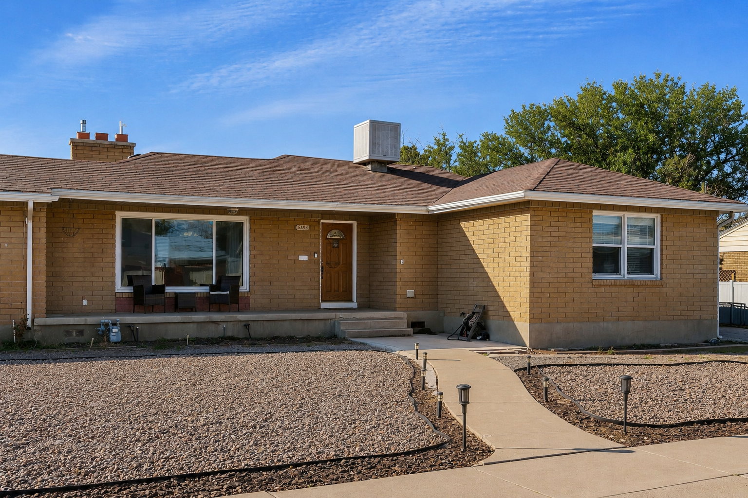 Brick exterior residence featuring a front porch, an arched entry door, and a paved walkway with integrated outdoor lighting