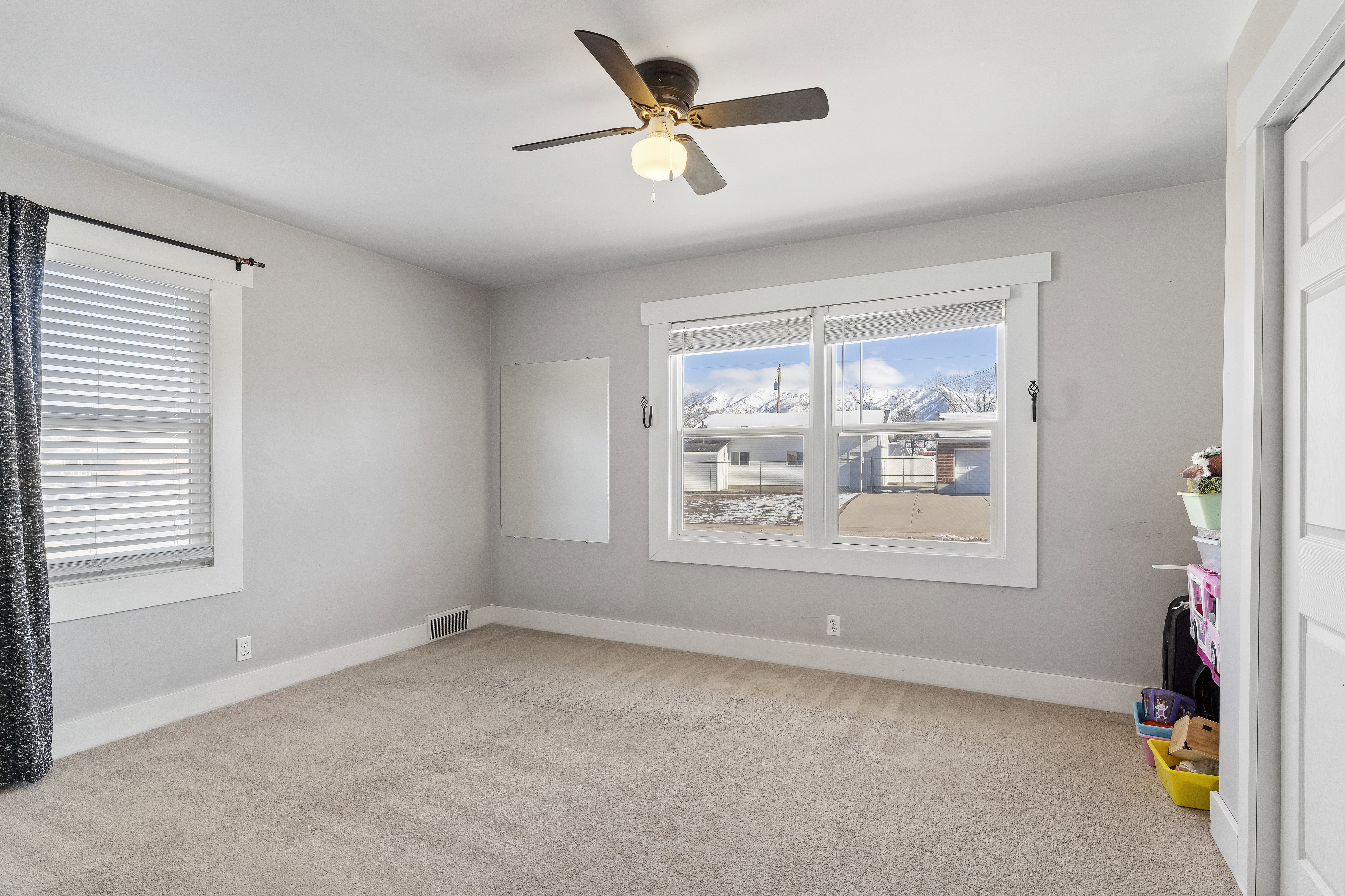 Carpeted room featuring dual windows with blinds, a ceiling fan, and a neutral wall color