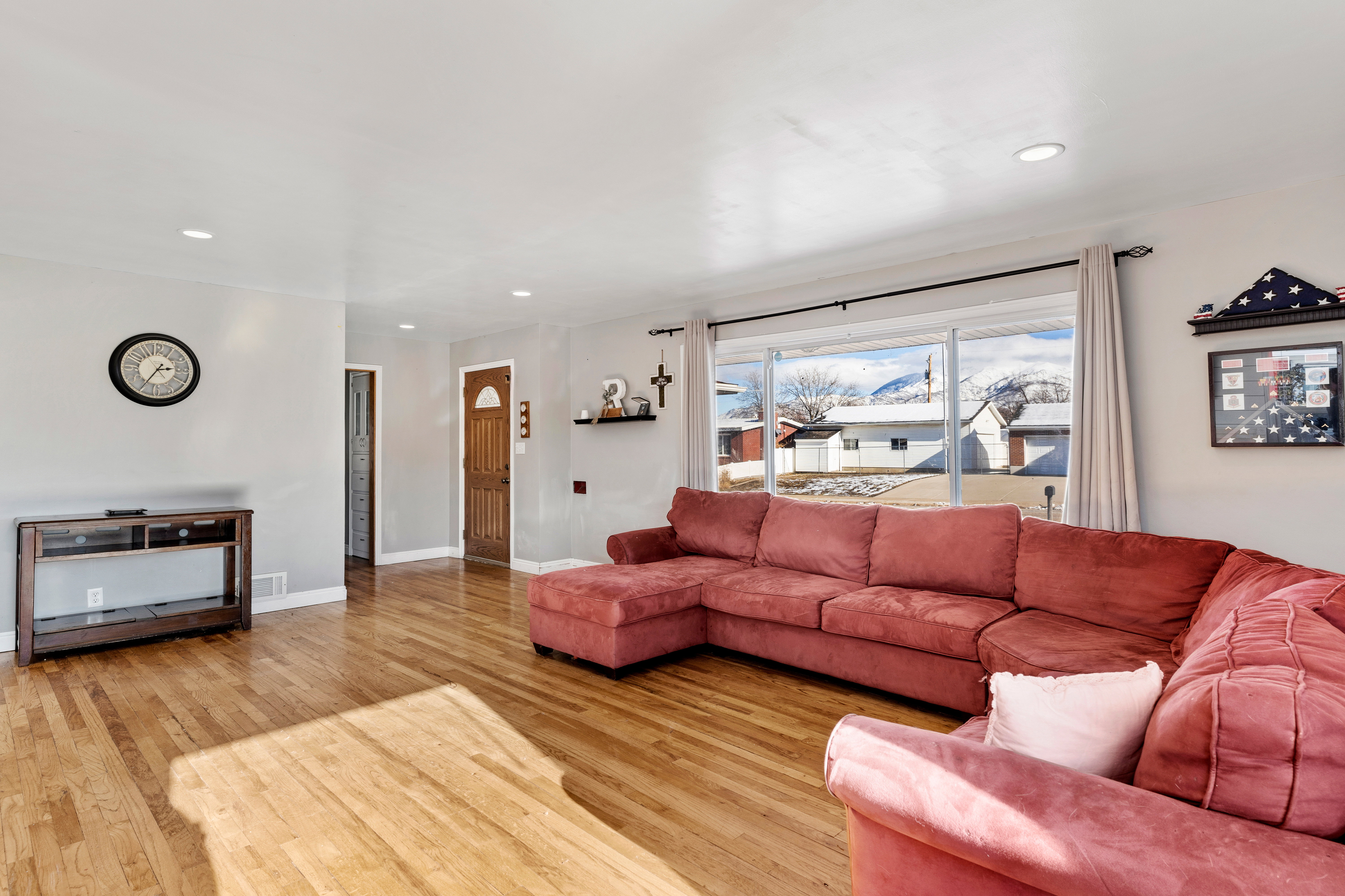 Living area featuring hardwood flooring, recessed lighting, white baseboards, and a large window