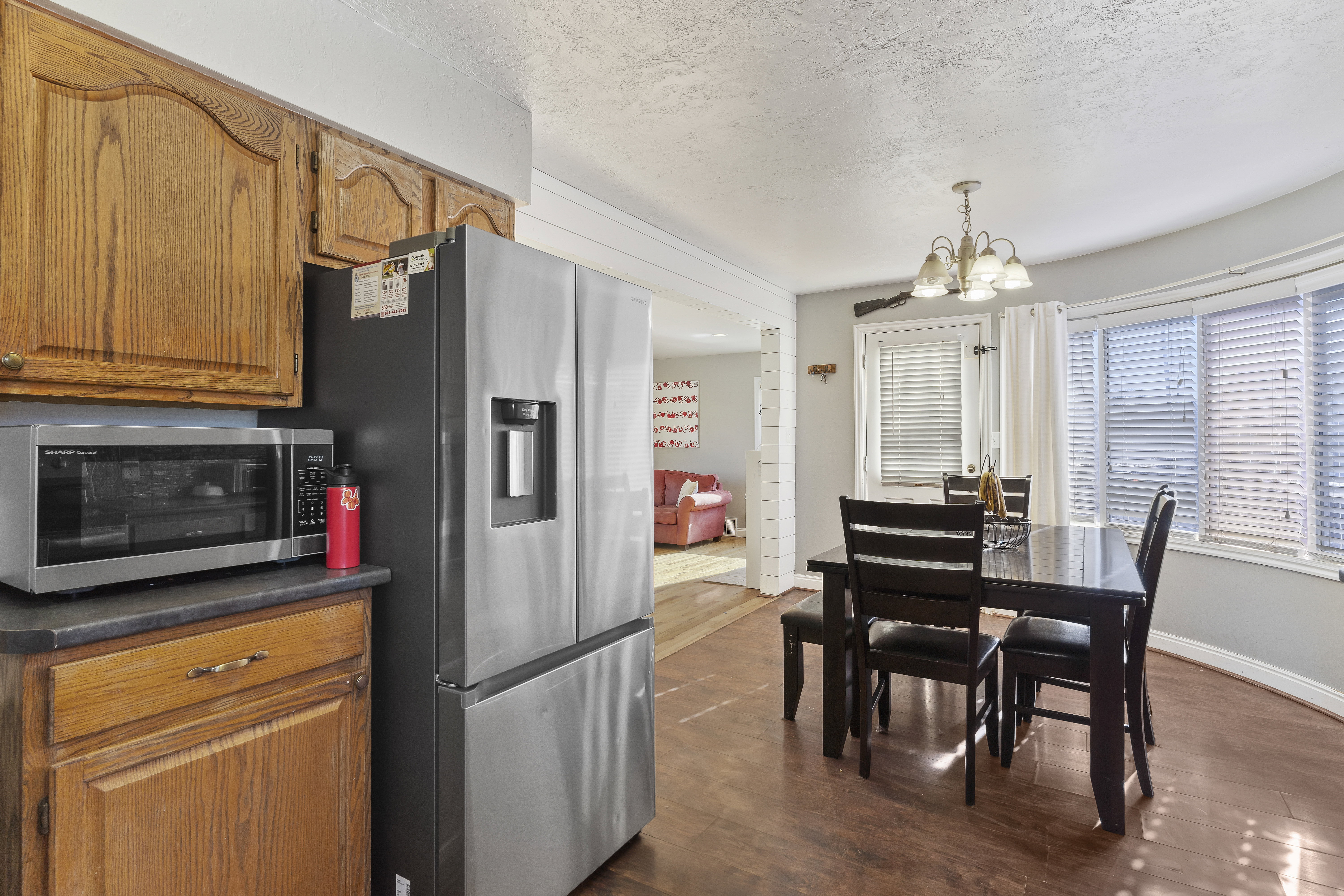 Kitchen and dining area featuring wood-finish flooring, oak cabinetry, and a stainless steel refrigerator