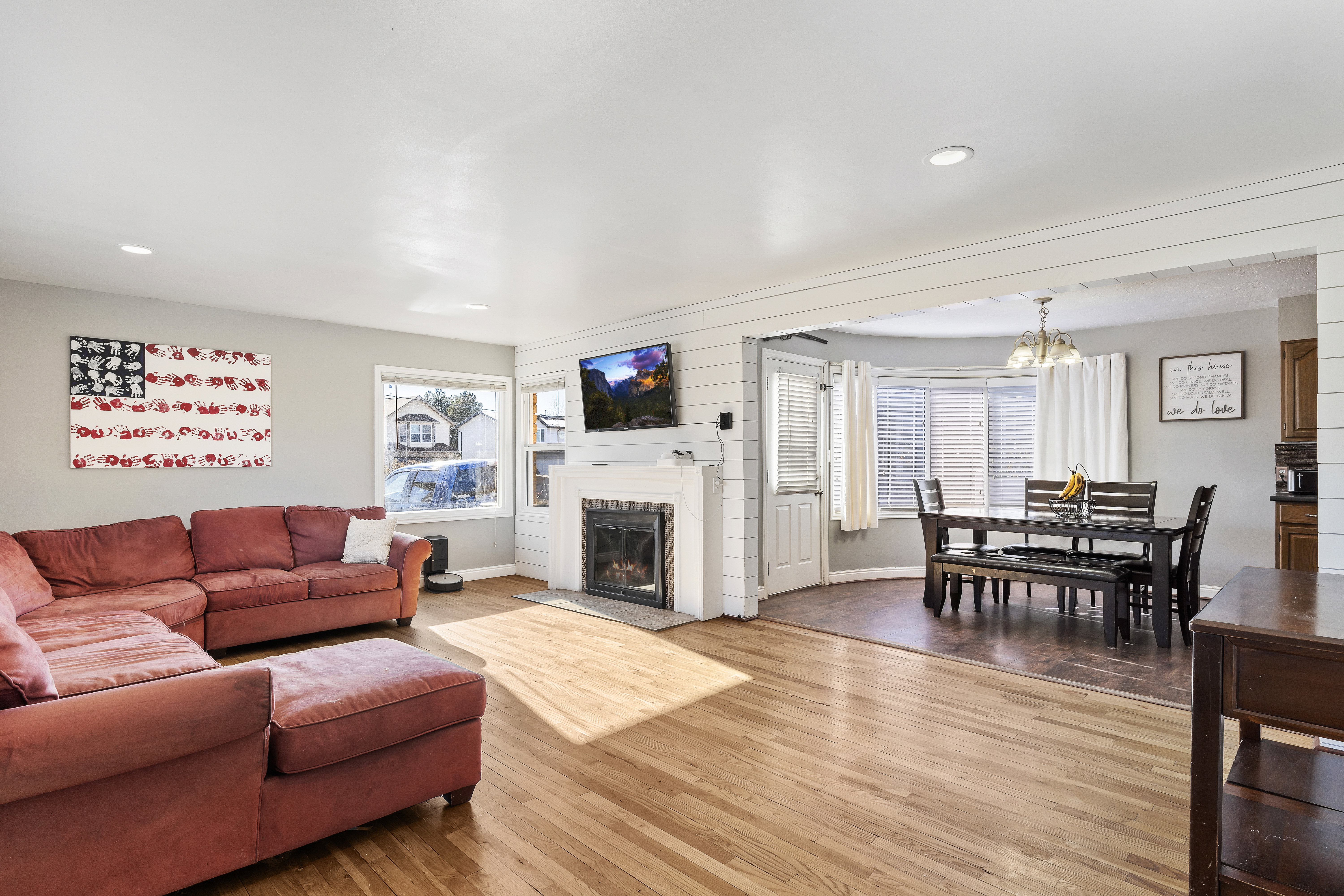 Open-concept living area featuring wood-finish flooring, recessed lighting, and a white brick fireplace