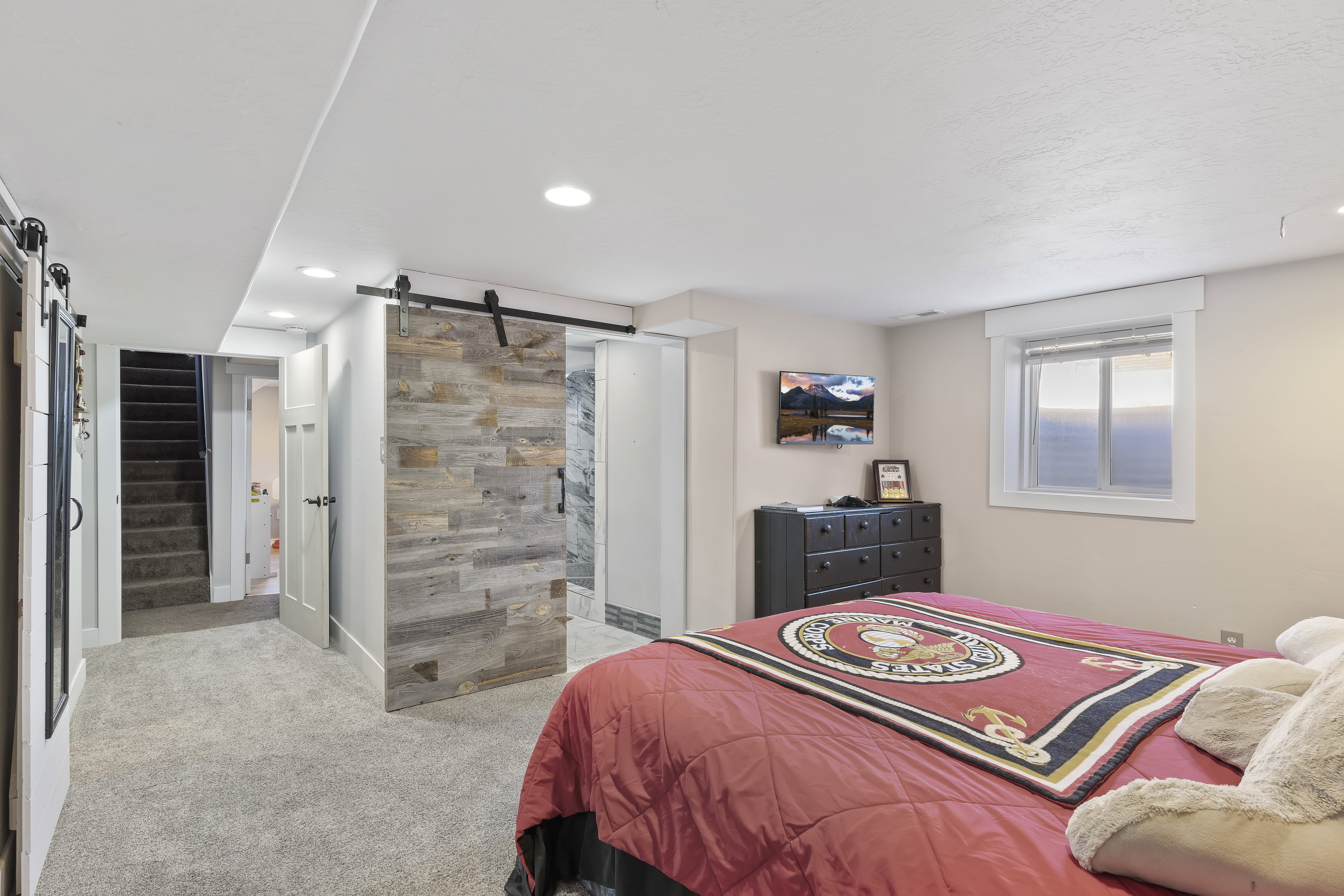 Carpeted room with a sliding barn door featuring a wood-finish facade