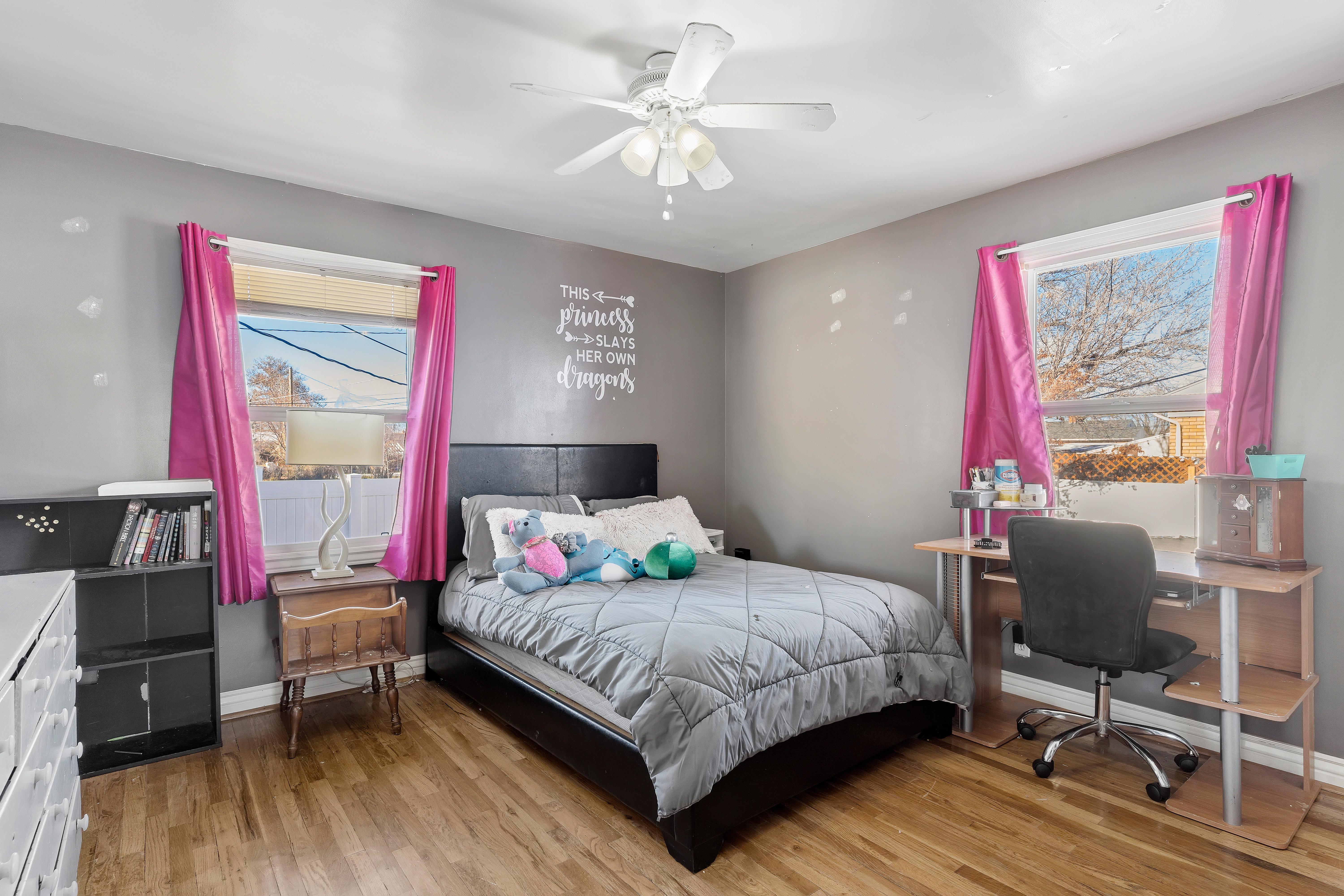 Bedroom featuring wood-finish flooring, two window openings, and a ceiling fan