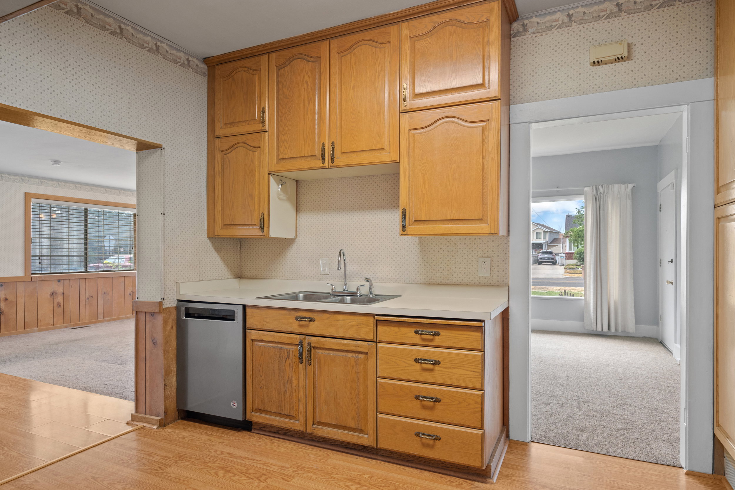 Kitchen featuring wood cabinetry, a stainless steel sink with a chrome faucet, and light-colored countertops