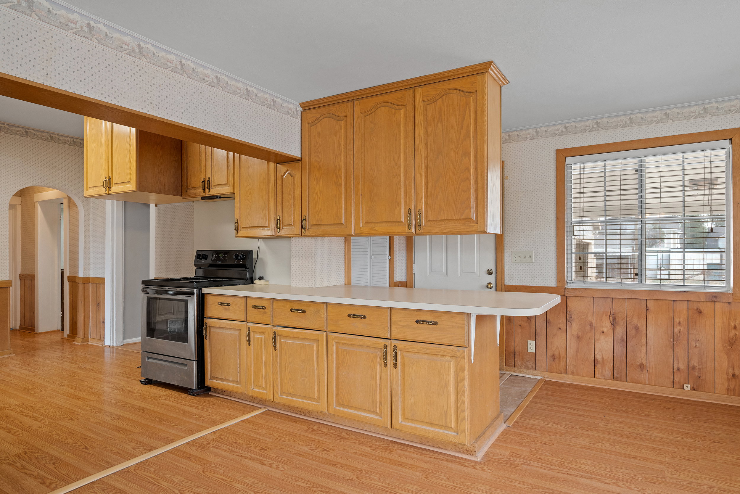 Kitchen featuring wood-finish cabinetry, a white countertop with an extended breakfast bar, and a stainless steel range