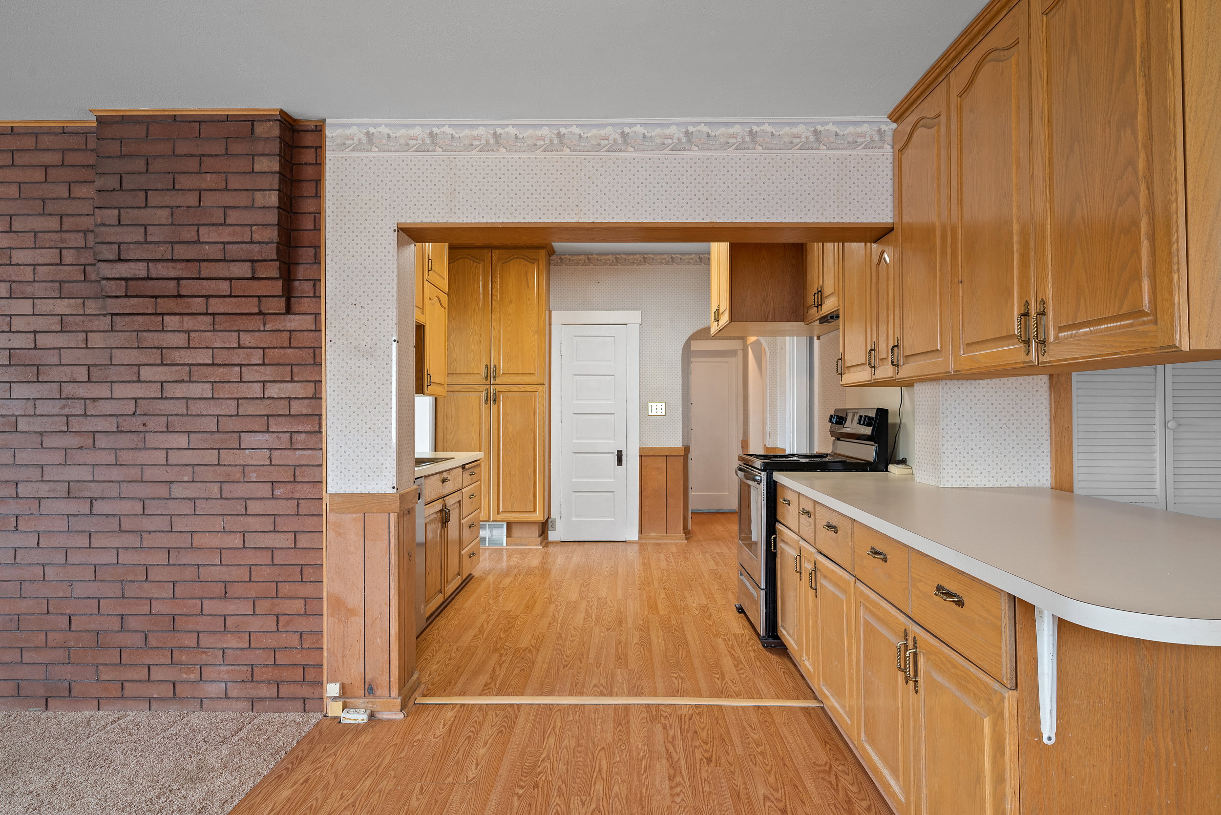 Kitchen featuring wood-finish flooring, wood cabinetry, white countertops, and a stainless steel range